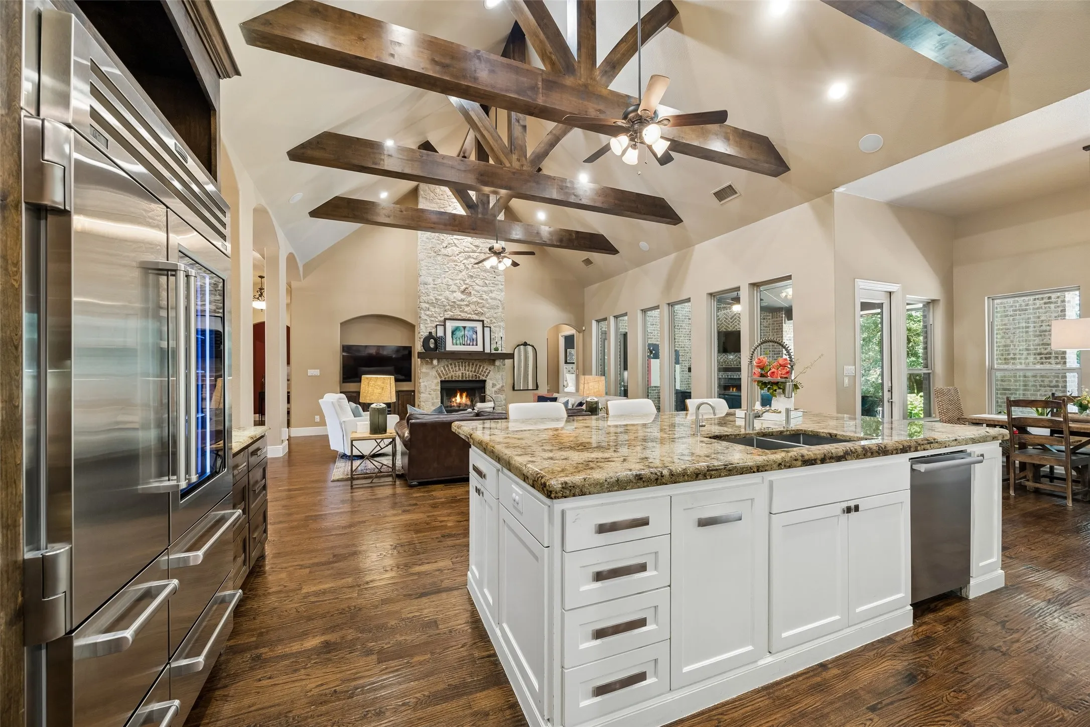 Gourmet kitchen island with stone countertops, integrated sink, and white cabinetry