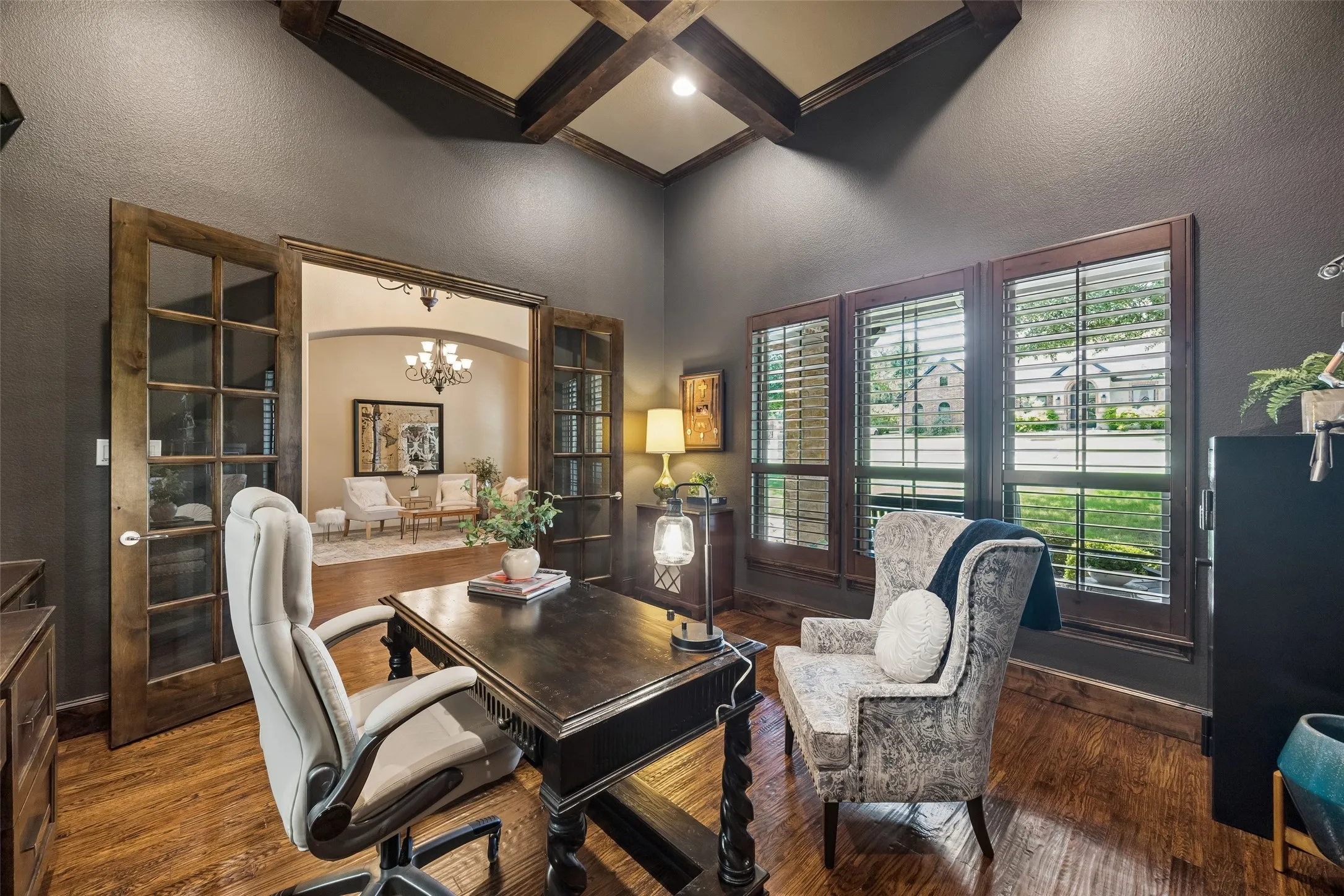 Dedicated office space featuring rich wood-finish flooring, dark wall tones, and a vaulted ceiling with exposed wood beams