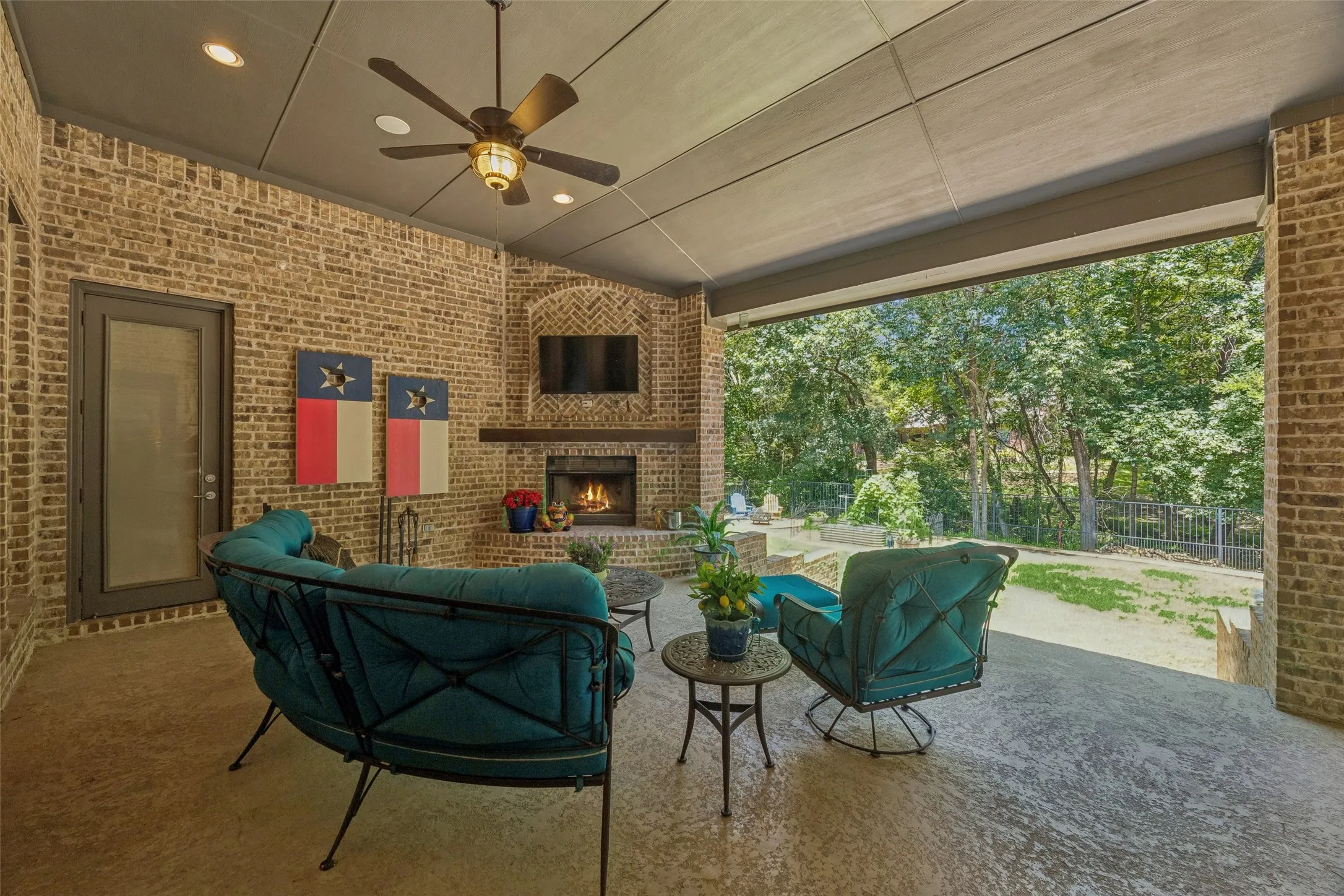 Expansive covered patio featuring a brick fireplace with a wood mantel, a ceiling fan with integrated lighting, recessed lighting, and a concrete patio floor