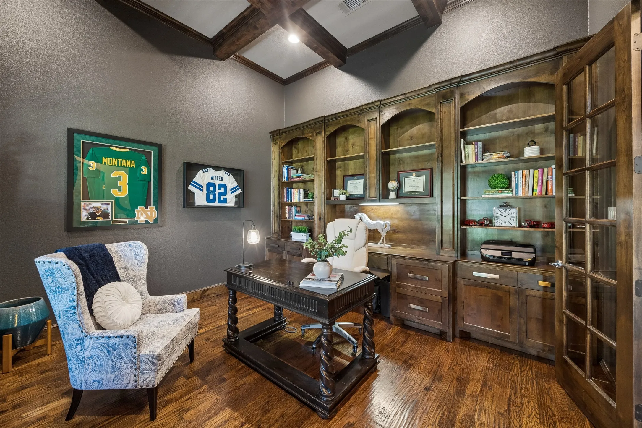 Dedicated workspace featuring built-in wood cabinetry, a wood-finish floor, exposed ceiling beams, and French doors