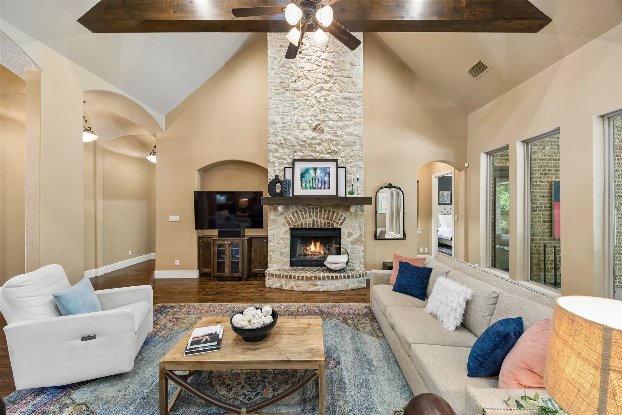Vaulted ceilings defining a living space with a stone fireplace, wood-finish mantel, and brick hearth