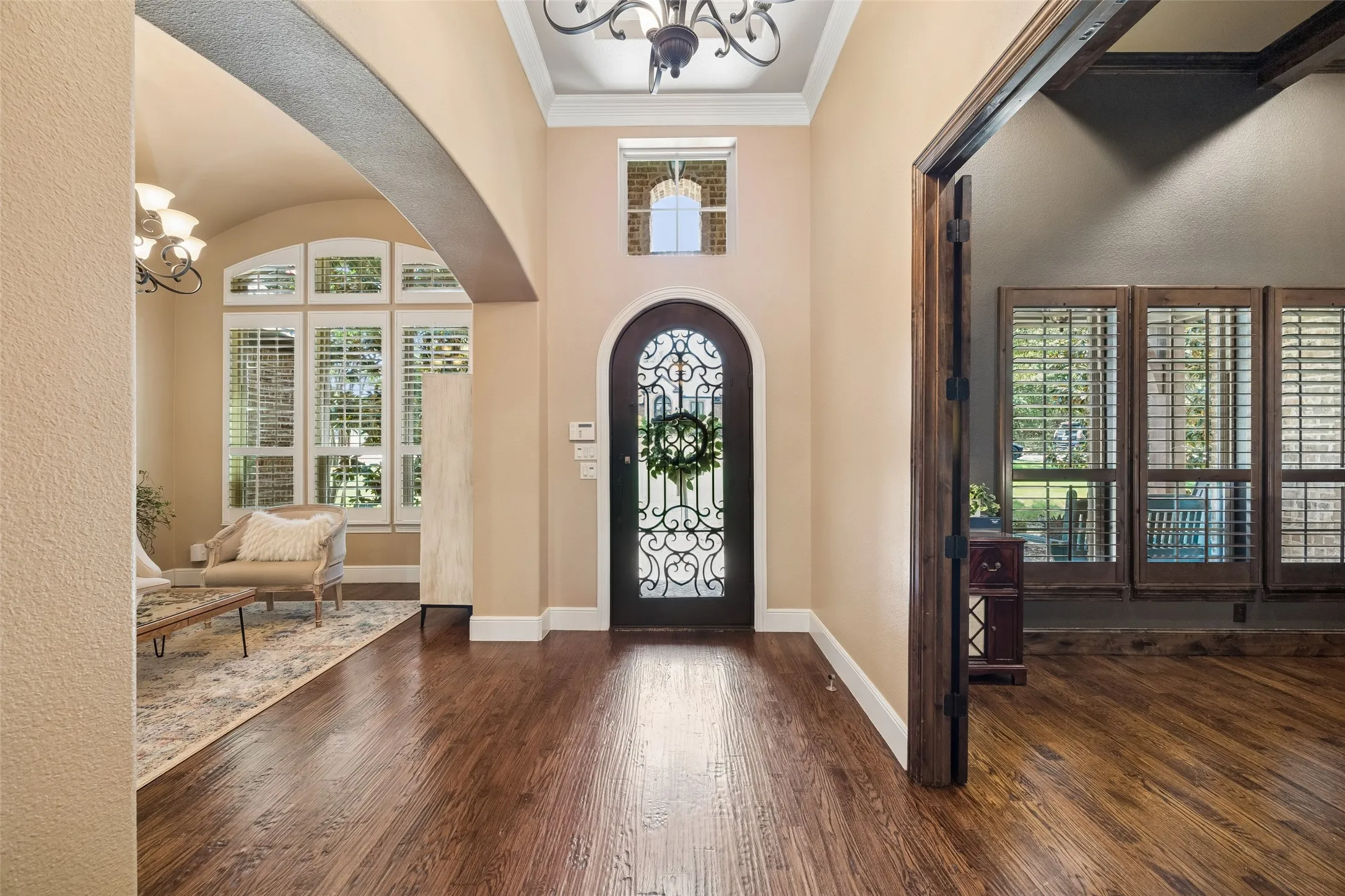 Grand entry foyer featuring wood-finish flooring, a decorative arched entryway, and a prominent arched door with intricate ironwork