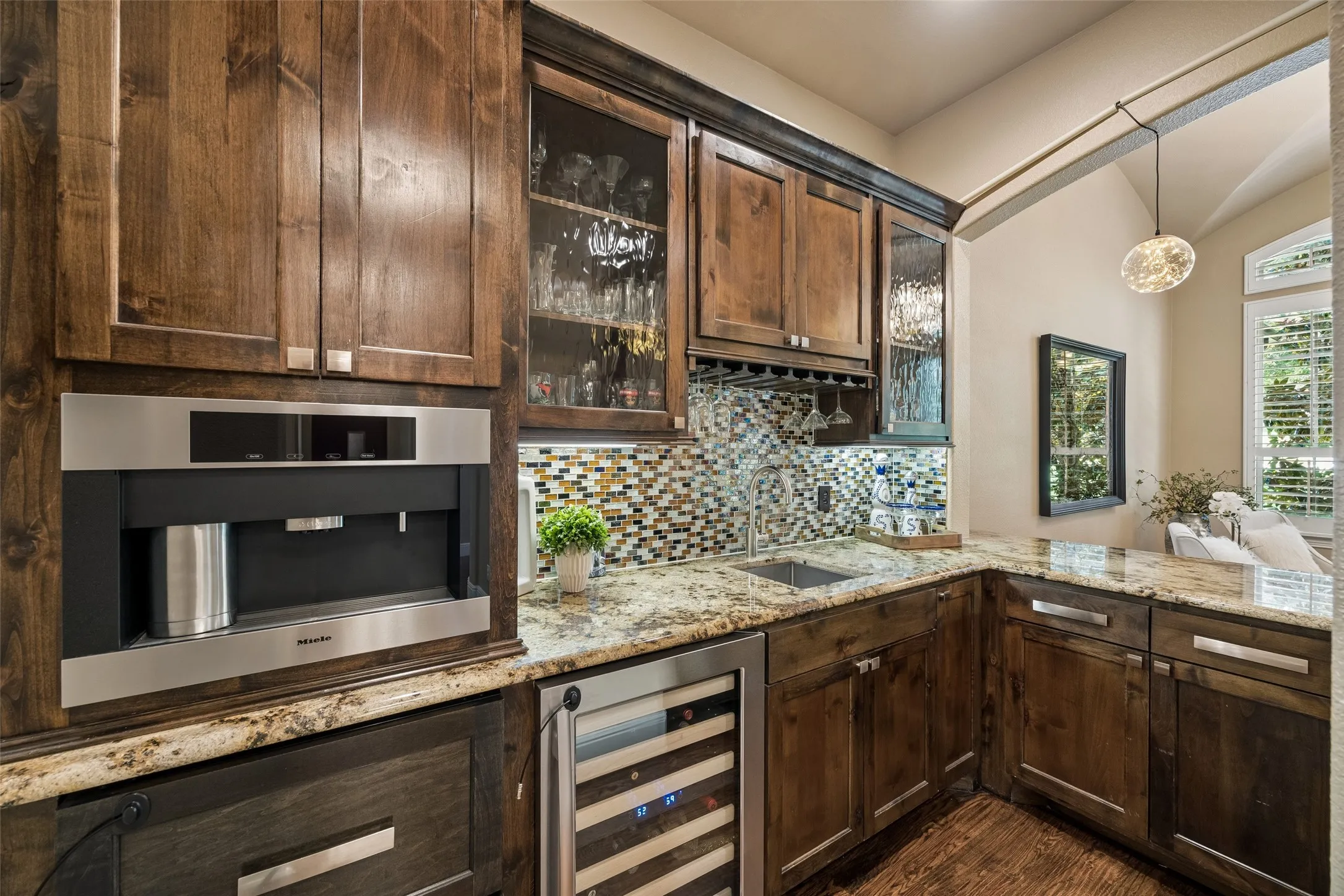 Custom beverage station featuring a built-in Miele coffee system, integrated wine refrigerator, and a mosaic tile backsplash
