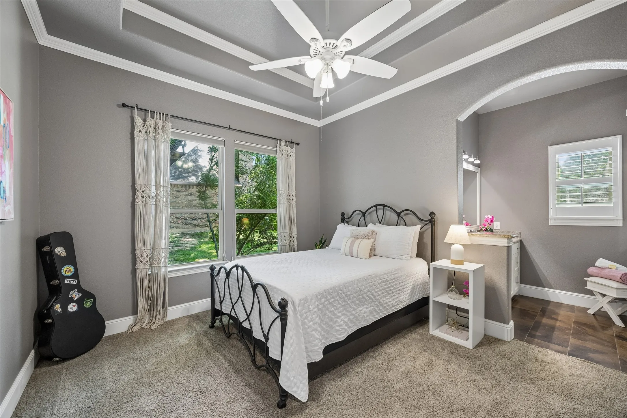 Bedroom featuring textured gray carpeting, a coffered ceiling with a ceiling fan, and two large windows offering abundant natural light