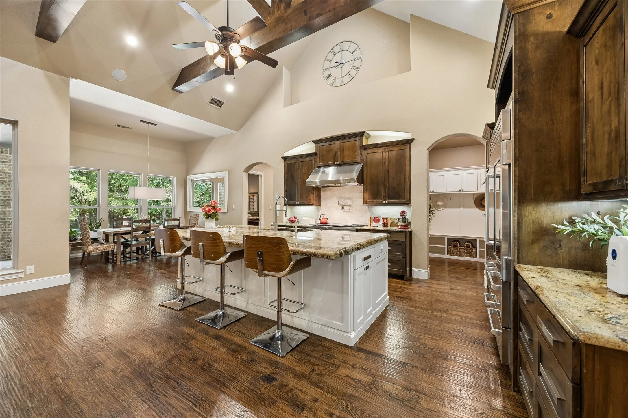 Spacious kitchen featuring a large central island with seating, granite countertops, and wood-finish flooring