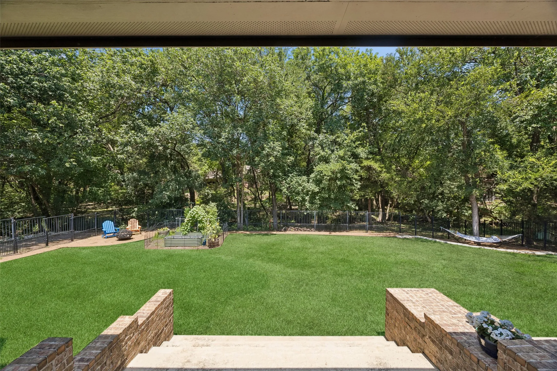 Expansive backyard featuring a lush lawn, mature trees, and a perimeter fence