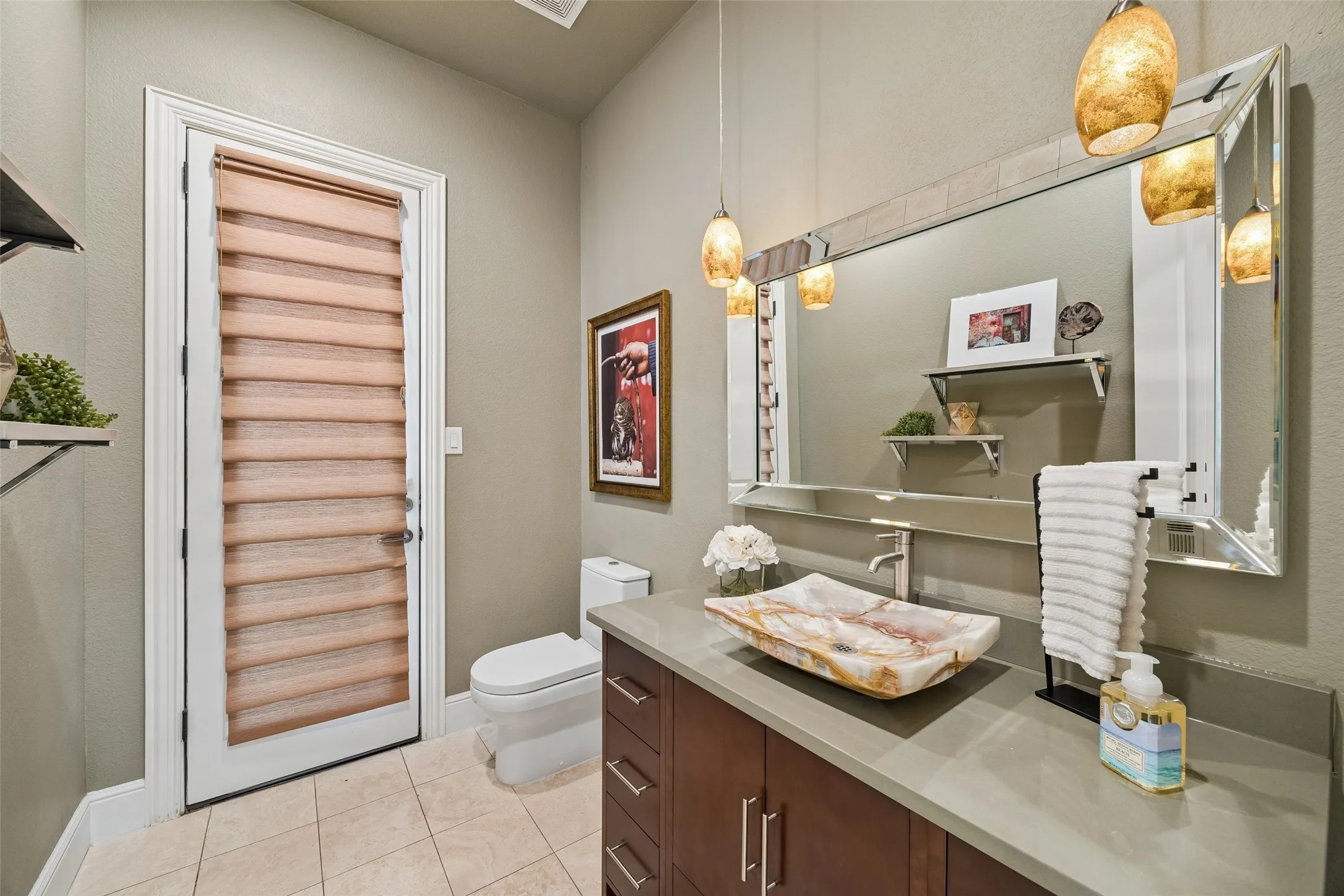 Bathroom featuring a wood-finish vanity with a light-colored countertop and a unique vessel sink