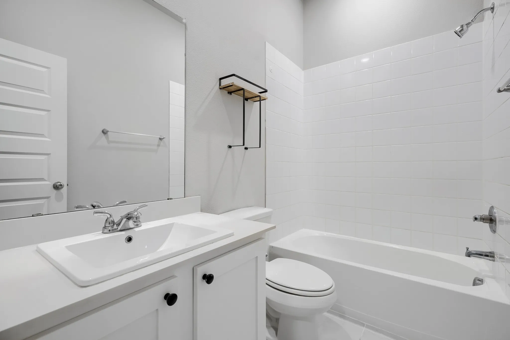 Bathroom featuring a white vanity with an integrated sink, polished chrome faucet, and black cabinet hardware