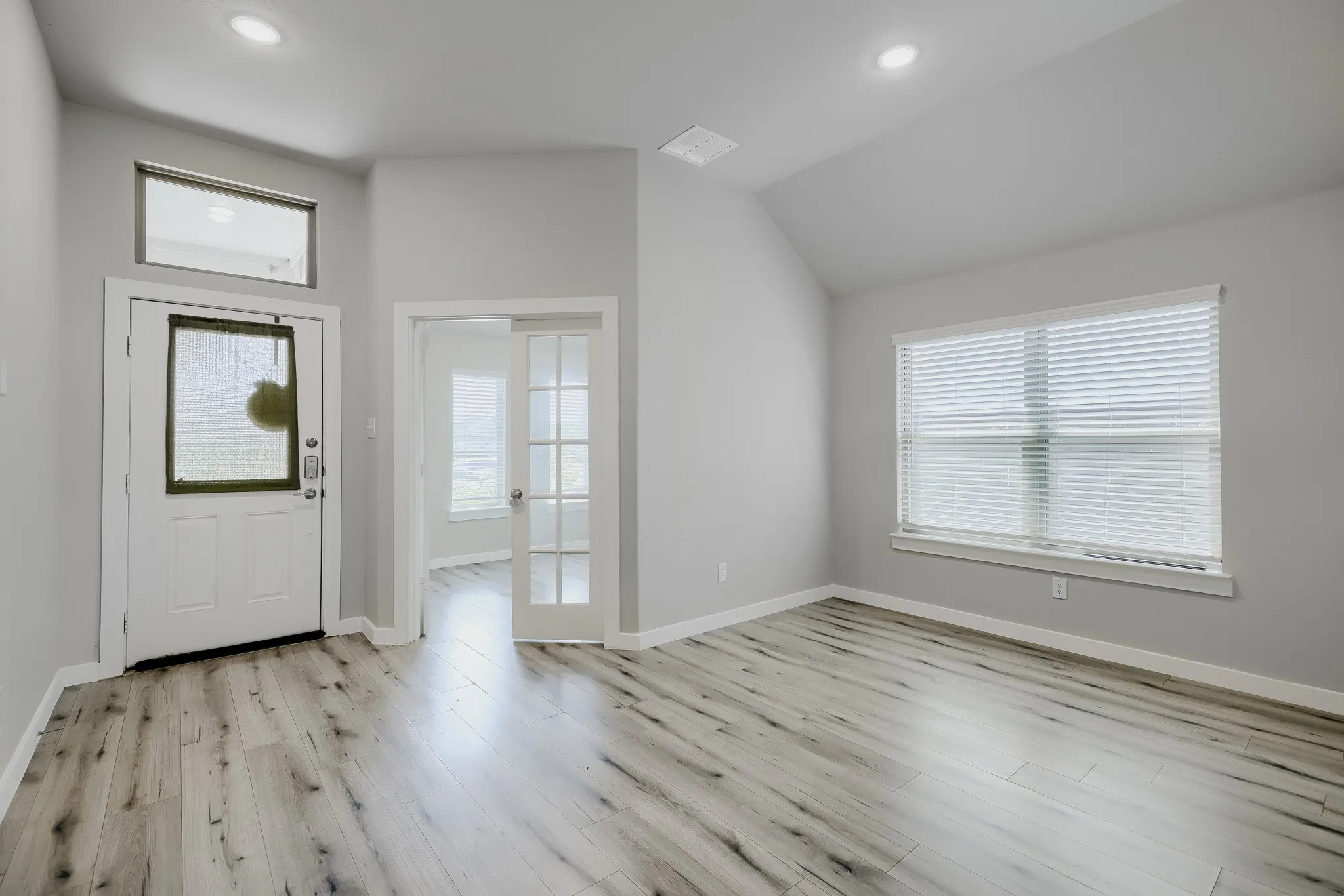 Entryway featuring wood-finish flooring, a white paneled door with a transom window, and recessed lighting