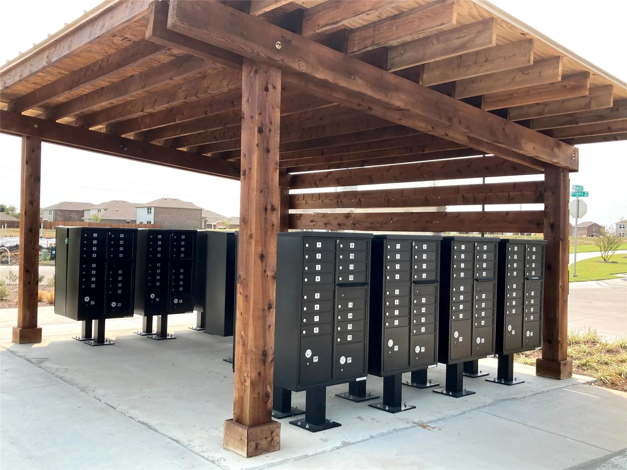 Covered community mail kiosks with exposed wood beam construction, slatted wood privacy screen, and concrete pad