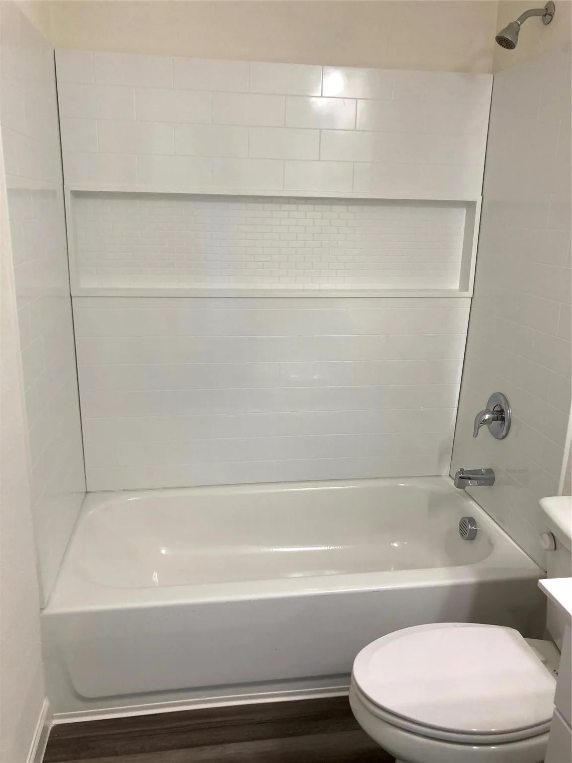 Bathroom featuring a built-in tub and shower combination with white subway tile surround and an integrated niche with mosaic tile