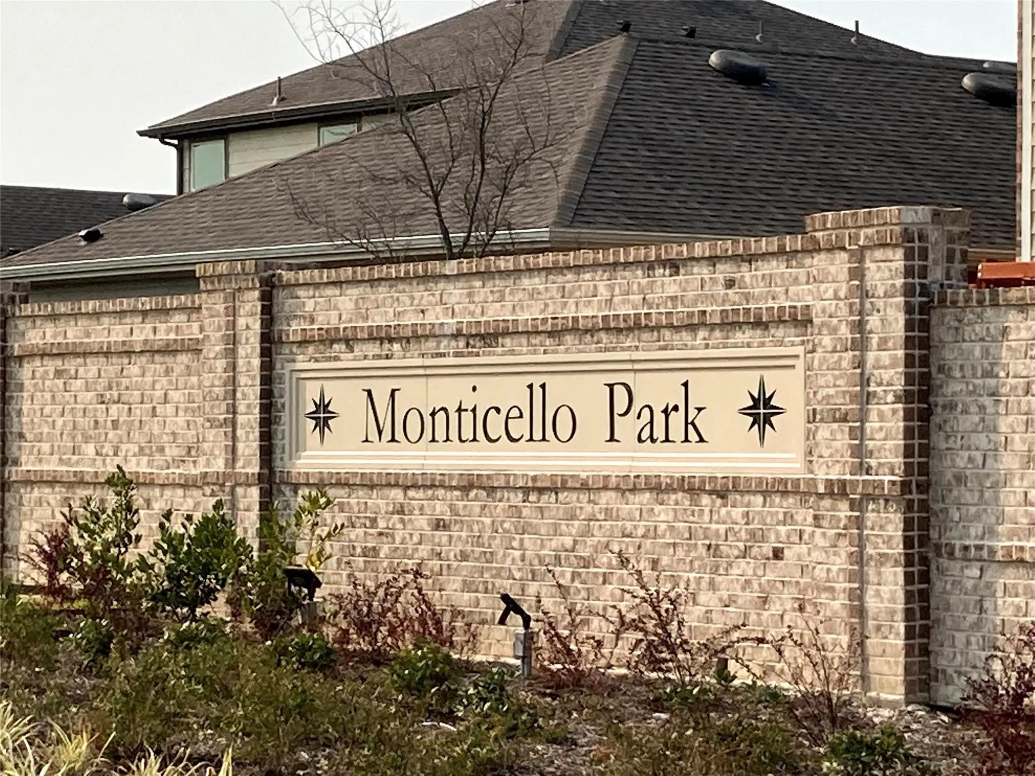 Monticello Park community entry sign featuring brick construction, decorative light-toned signage, and integrated landscaping