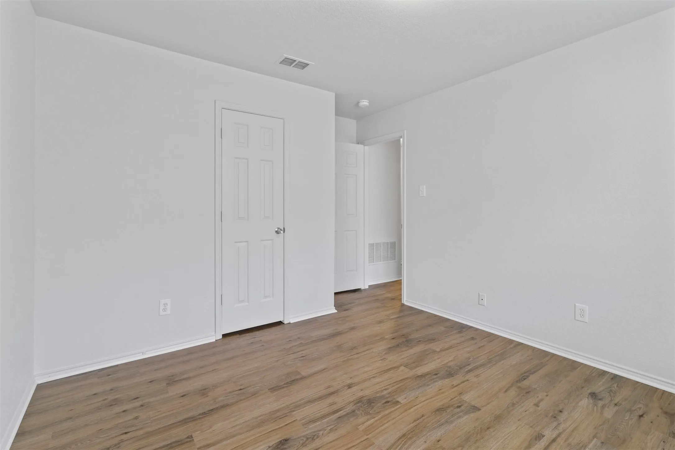 Room featuring wood-finish flooring, white baseboards, and neutral wall paint