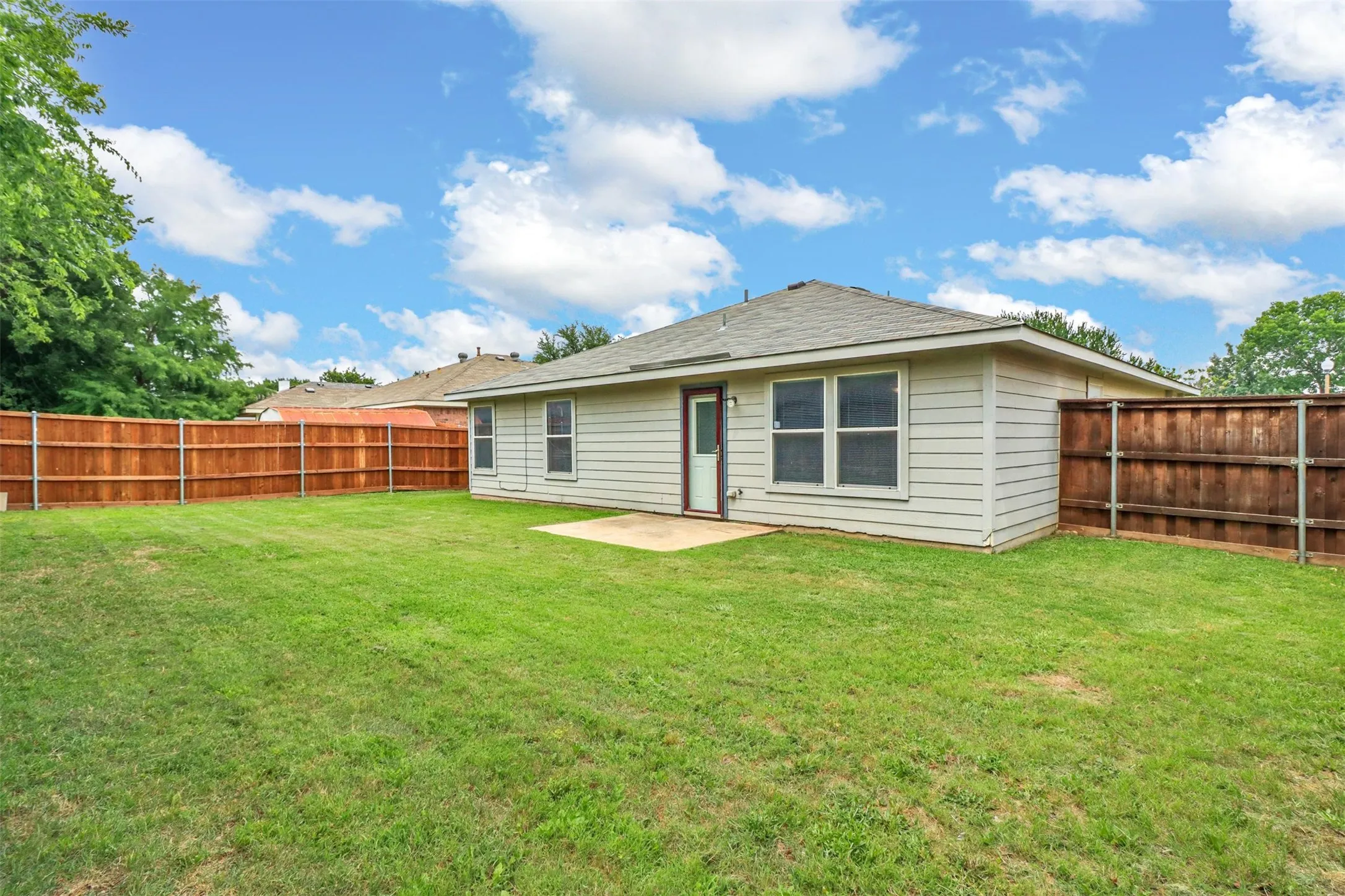 Expansive grassy backyard featuring a full perimeter wooden privacy fence