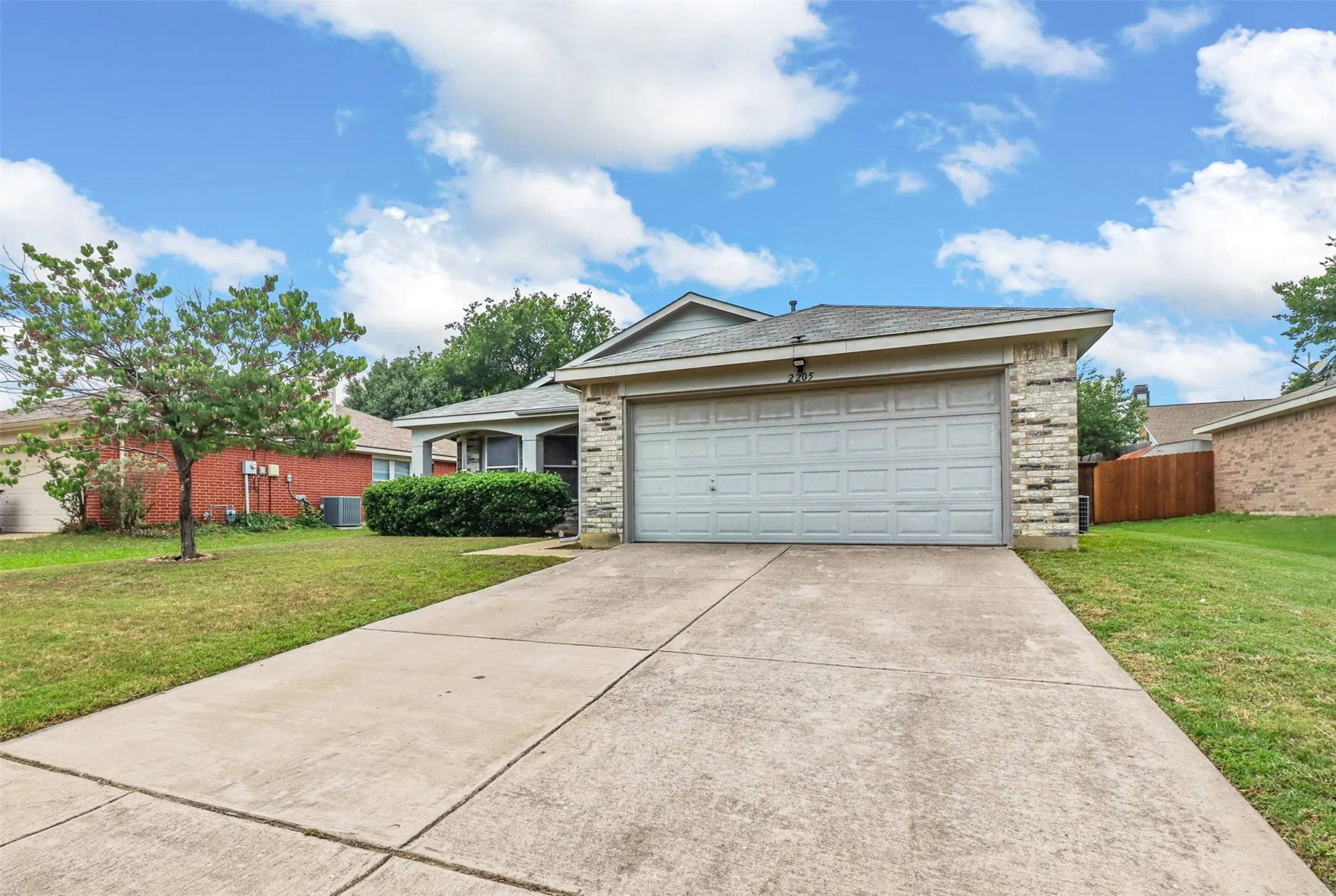 Front exterior featuring a two-car garage, concrete driveway, and stone facade accents