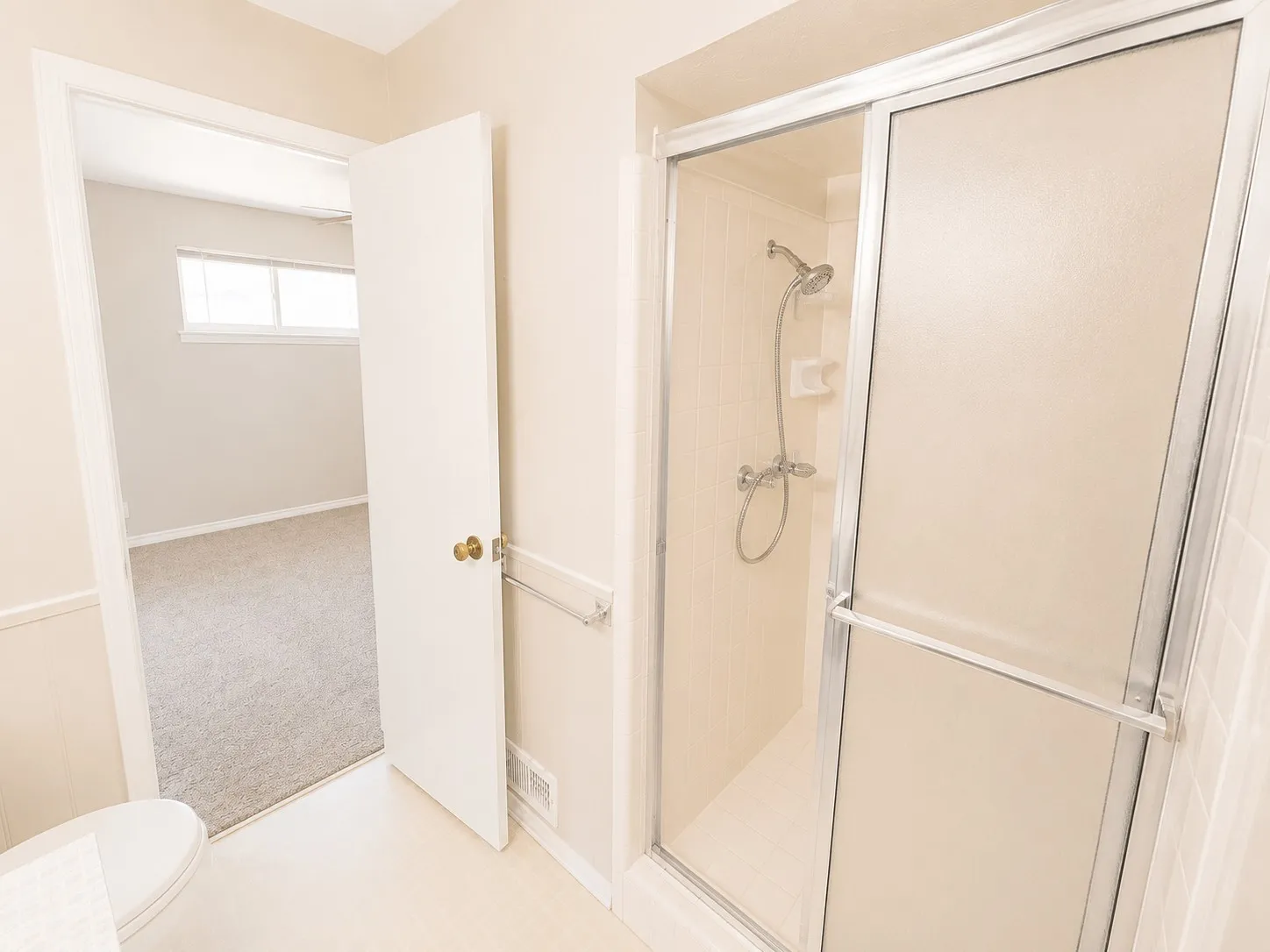 Bathroom featuring a standing shower with sliding glass doors, white tiled walls, and a chrome shower head