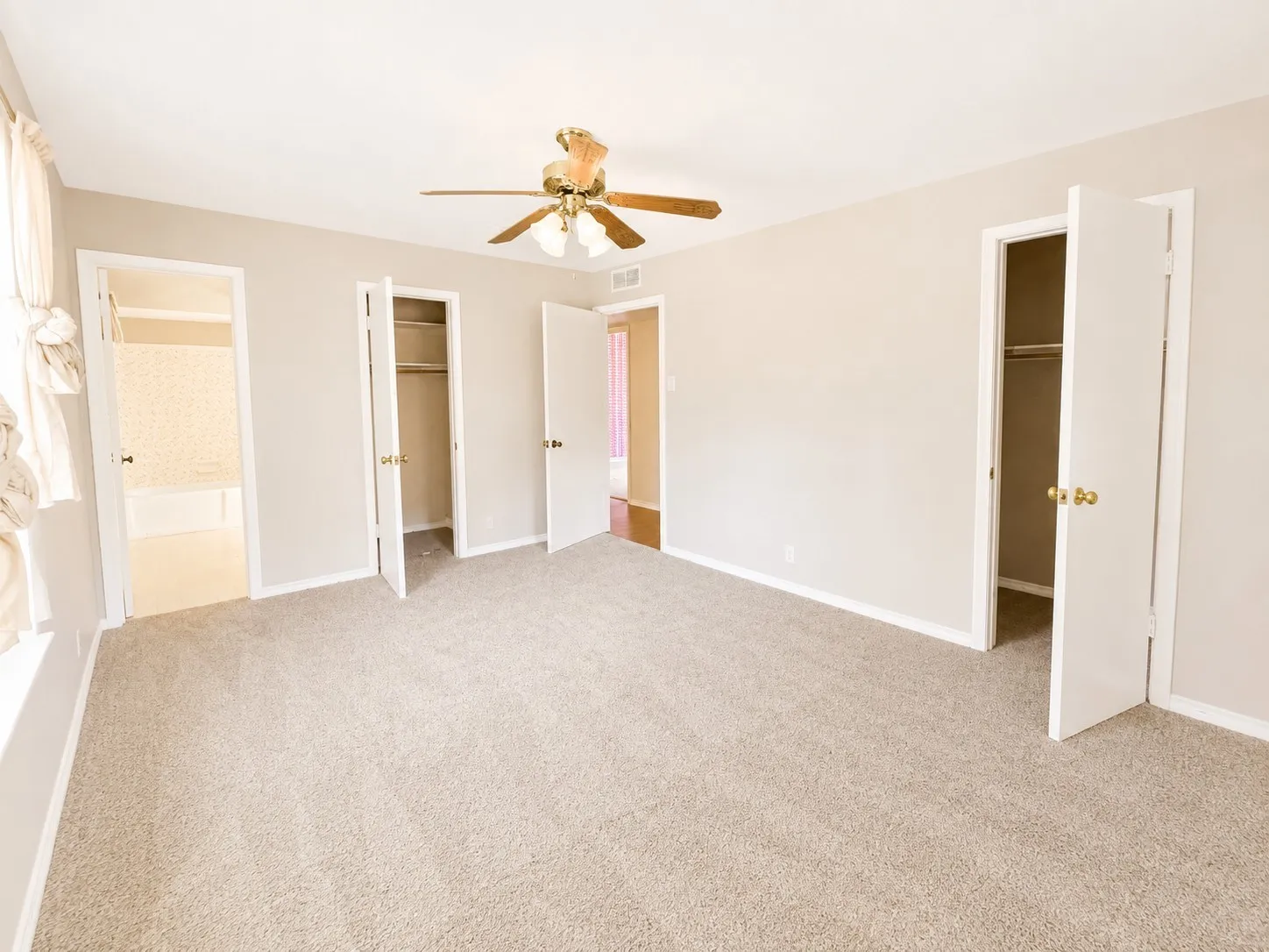 Carpeted room with neutral wall tones and a ceiling fan