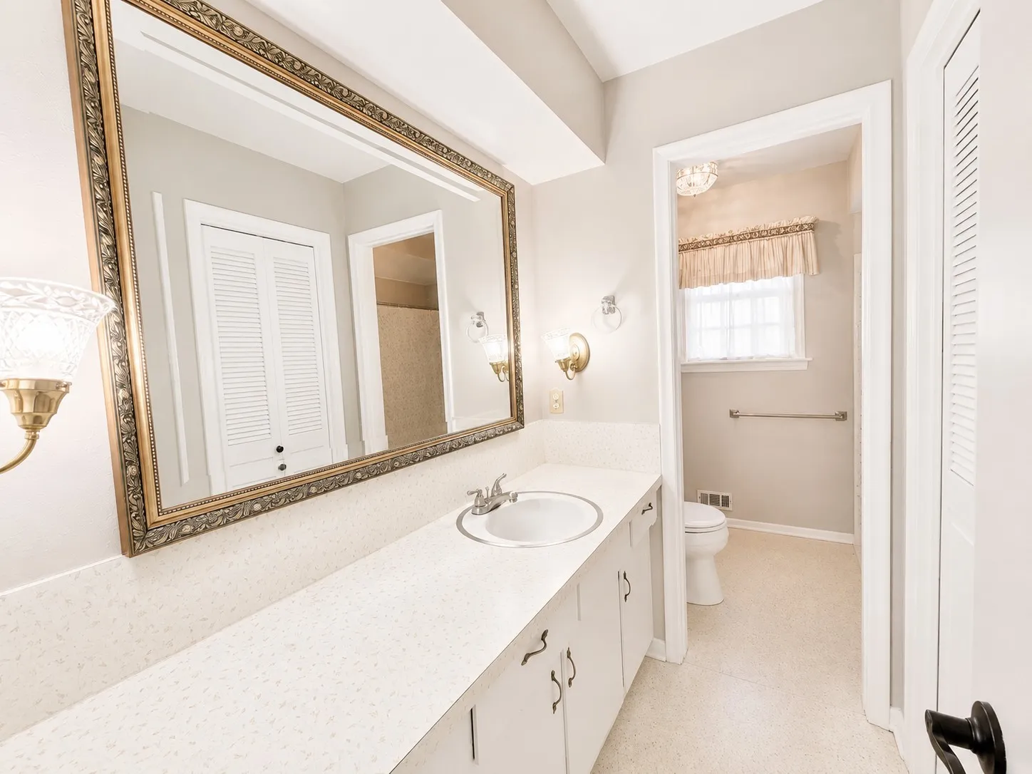 Bathroom vanity featuring a large ornate framed mirror, integrated sink, and ample countertop space