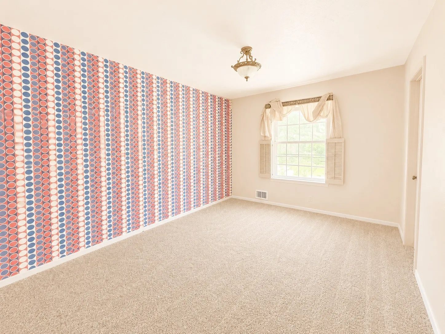 Room featuring patterned wallpaper accent wall, carpeted flooring, a ceiling-mounted light fixture, and a white-framed window