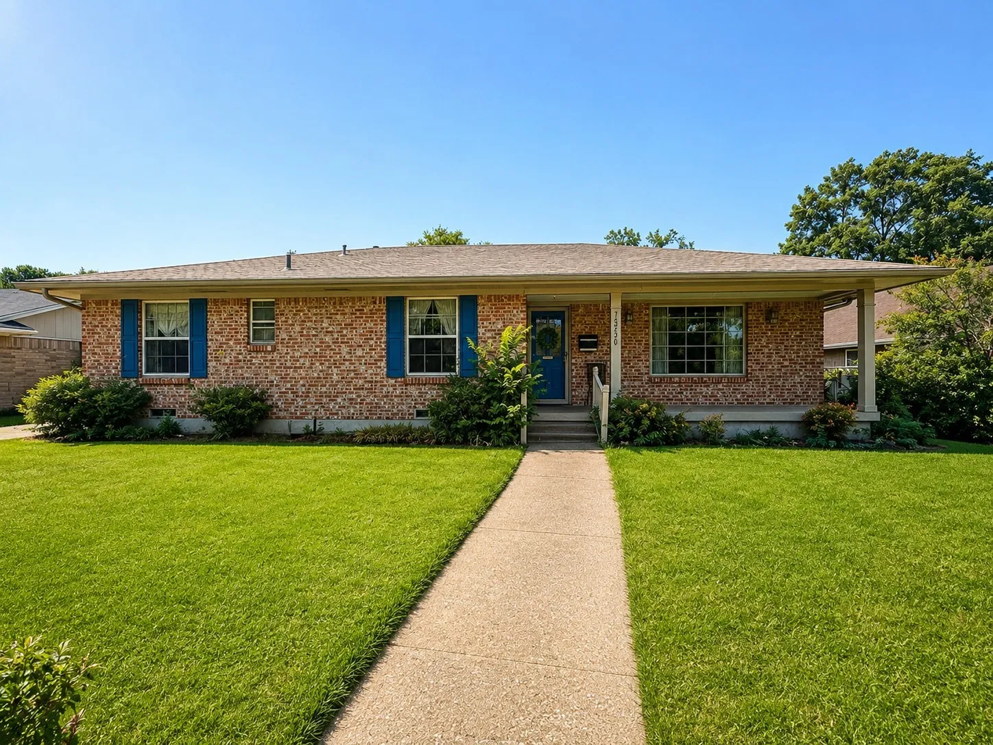 Brick ranch-style home featuring a covered front porch, blue front door, and matching blue window shutters