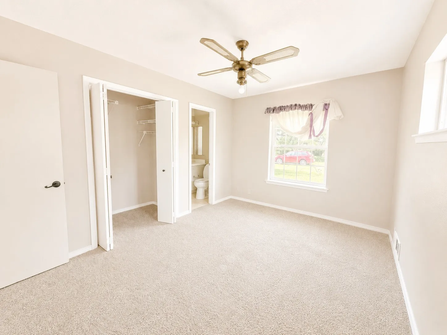 Carpeted room with a ceiling fan light fixture, a window, and a closet with bifold doors