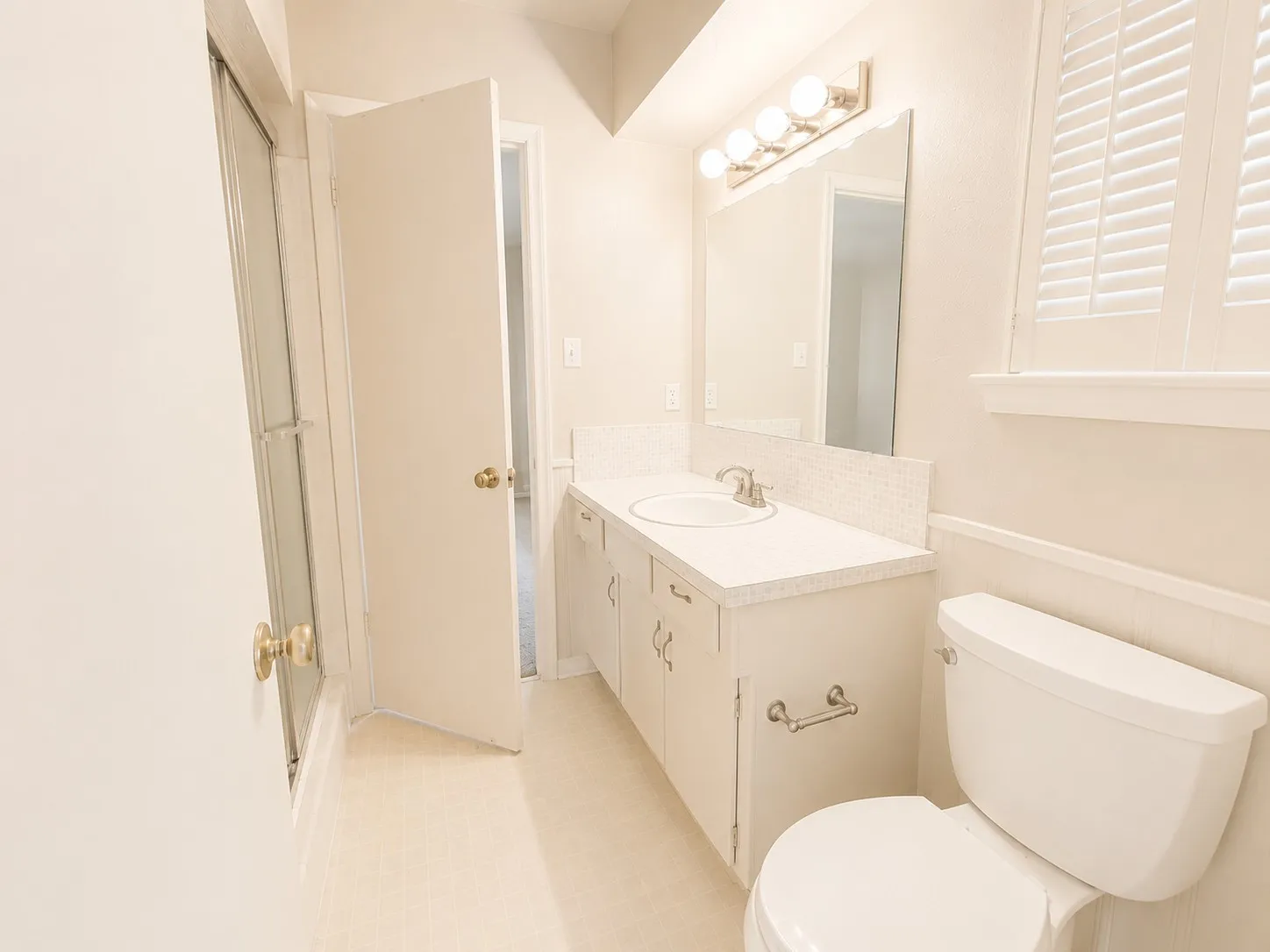 Bathroom with a white vanity, integrated sink, and white tile backsplash