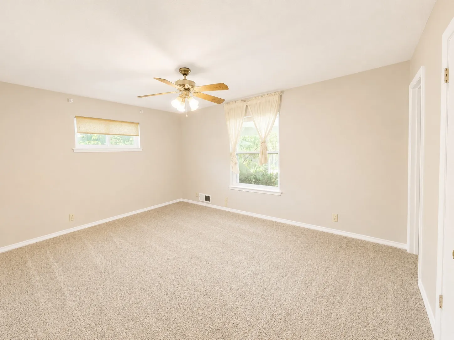 Carpeted room featuring neutral wall tones, two windows with natural light, a ceiling fan with integrated lighting, and white trim throughout