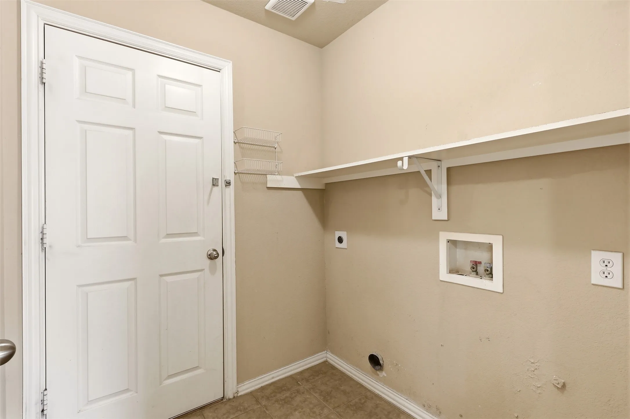 Dedicated utility space featuring a paneled door, built-in shelving, and utility hookups