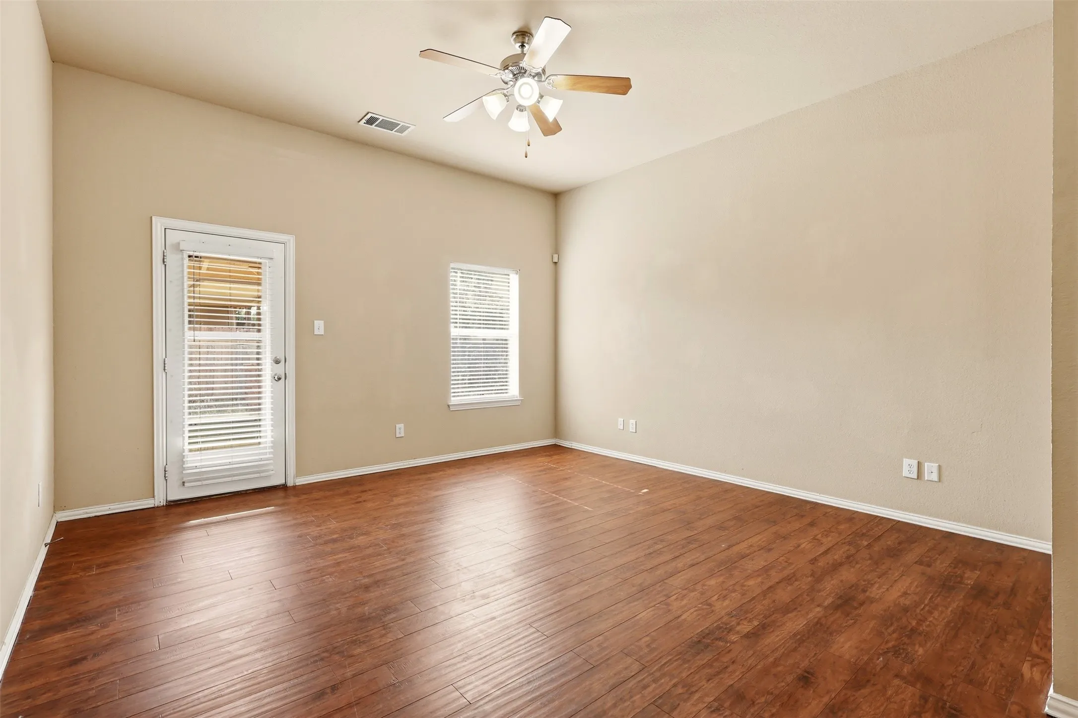 Spacious room featuring wood-finish flooring, vaulted ceiling, and a ceiling fan with integrated lighting
