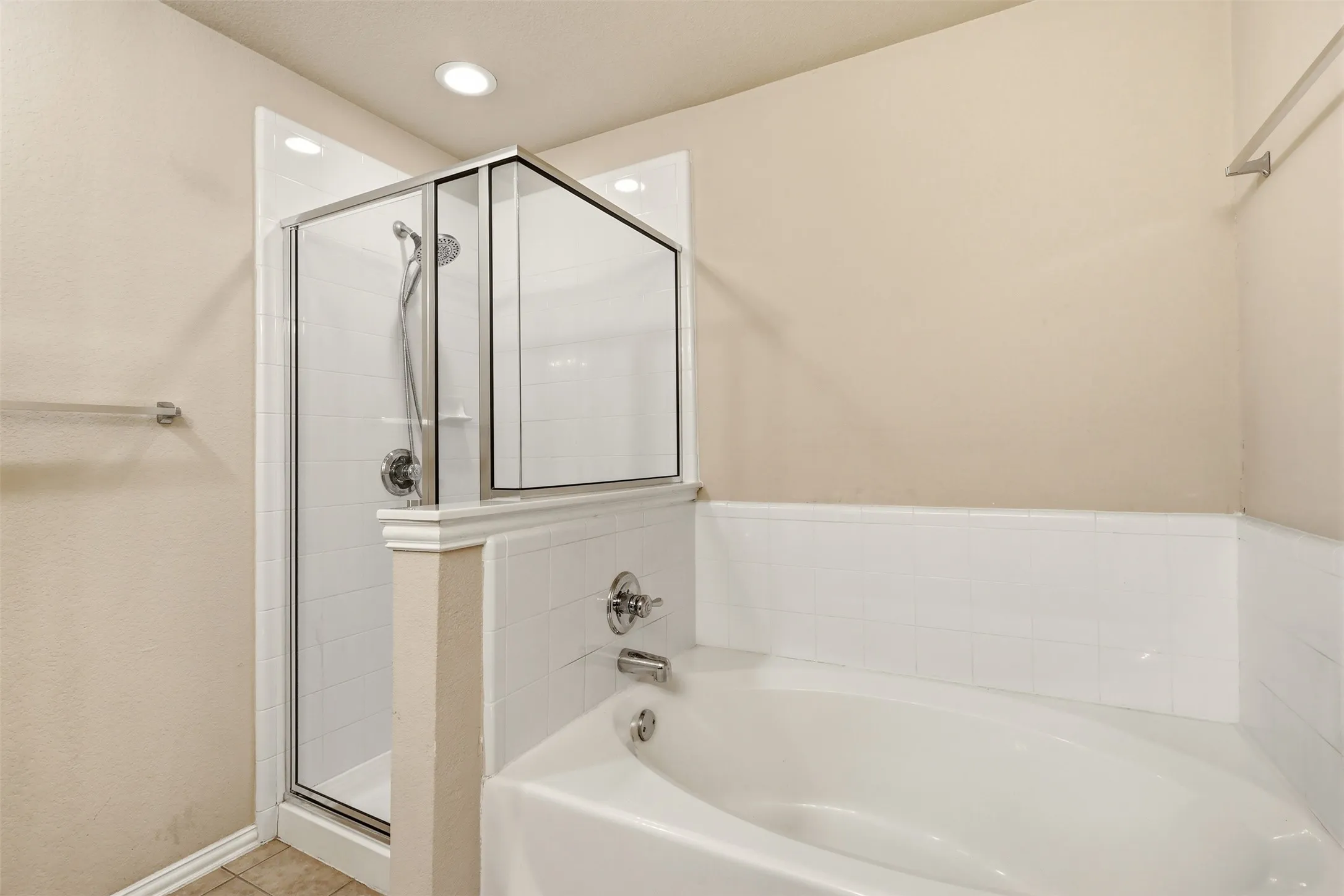 Bathroom featuring a built-in soaking tub and a glass-enclosed shower with tile surround