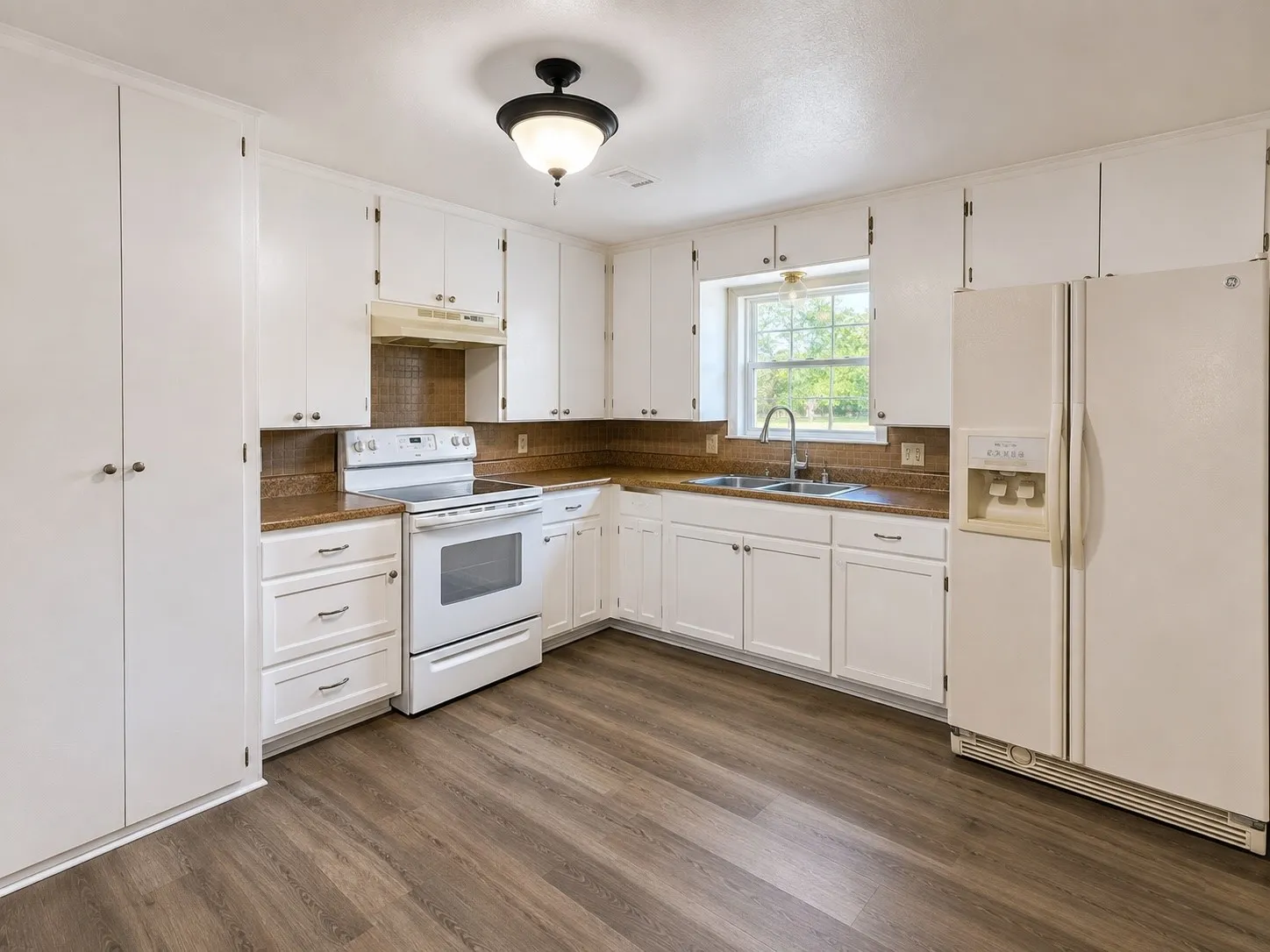 White cabinetry, wood-finish flooring, integrated sink, and kitchen window