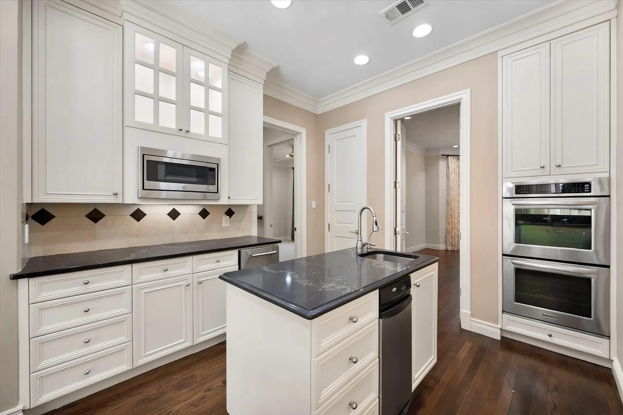 Lighted glass front cabinets, stainless appliances and double ovens, trash compactor and ice maker.