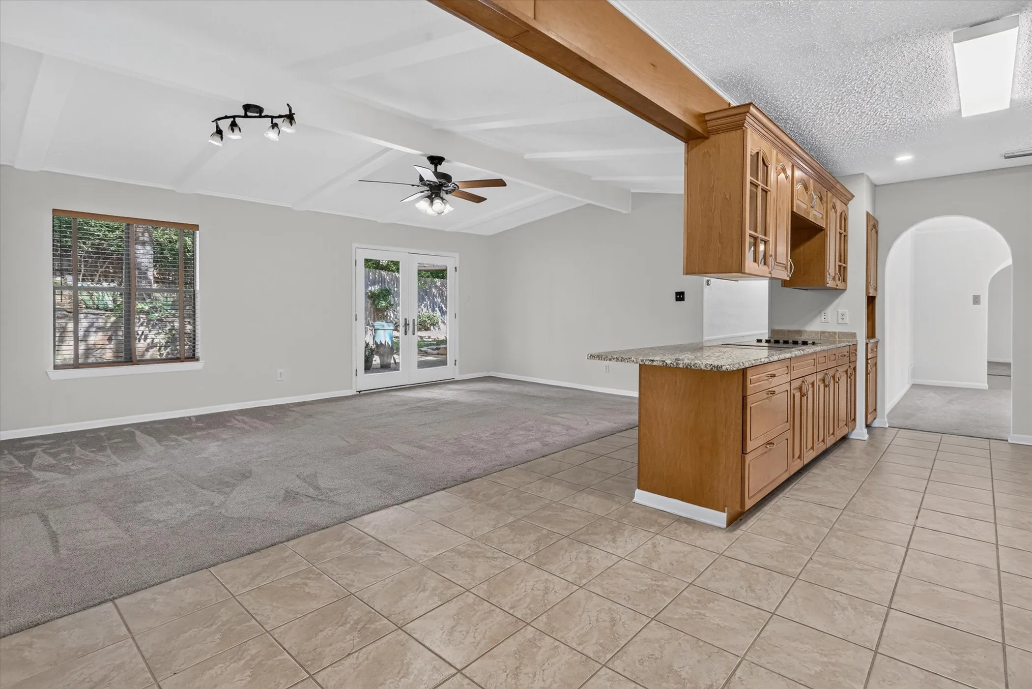 Open-concept living area with vaulted ceilings, exposed wood beam, and French doors