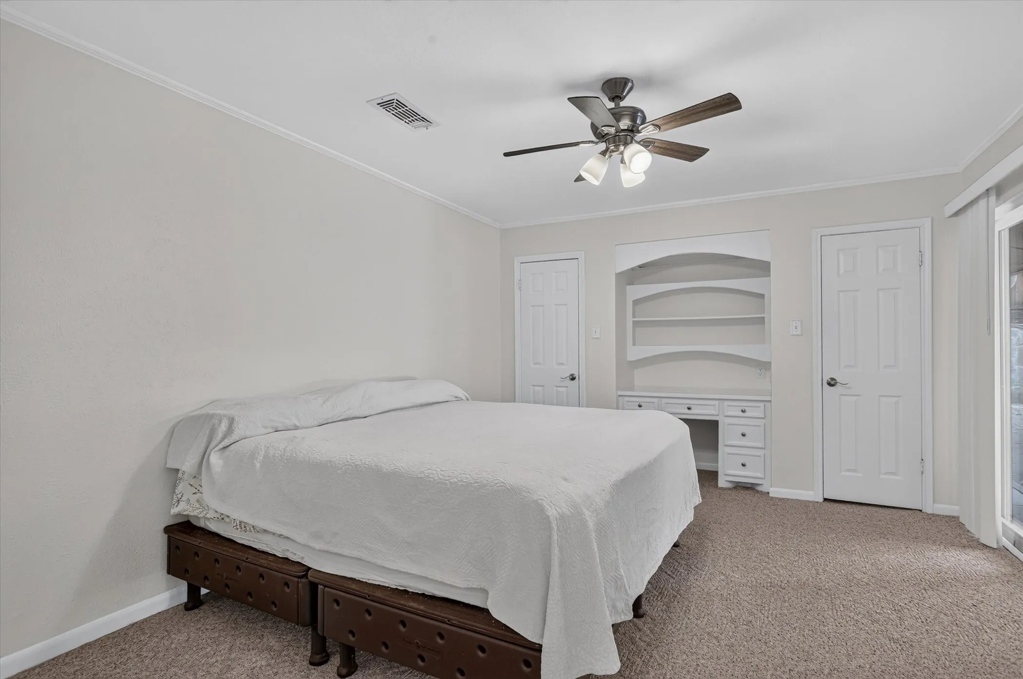 Built-in desk and shelving unit, ceiling fan, carpeted flooring, and white interior doors