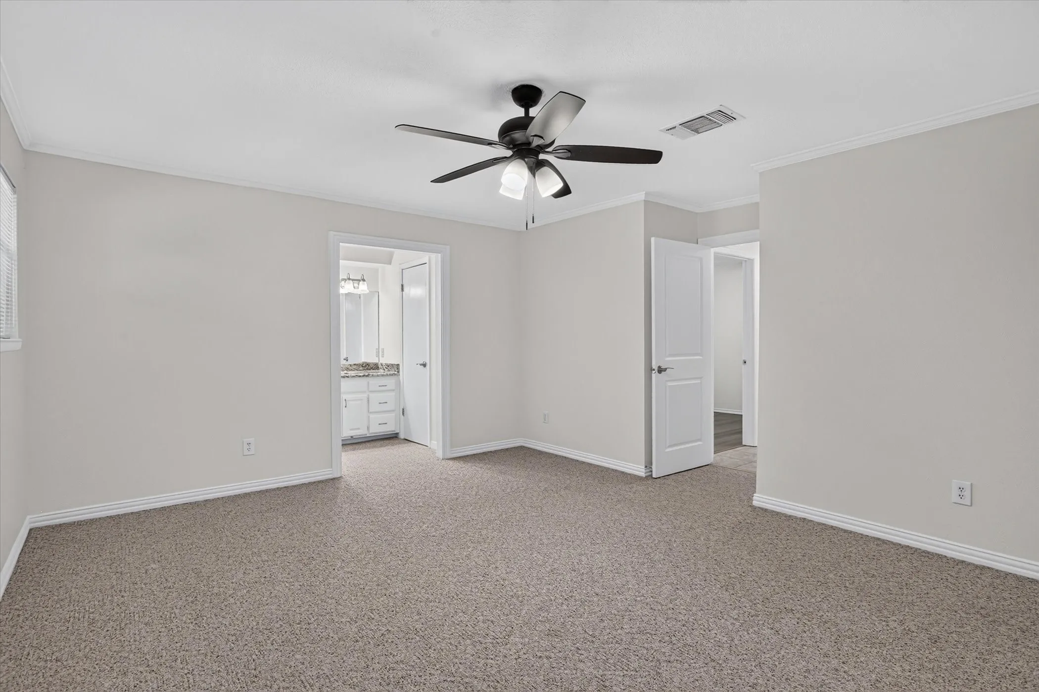 Carpeted room with a ceiling fan, white walls, and crown molding