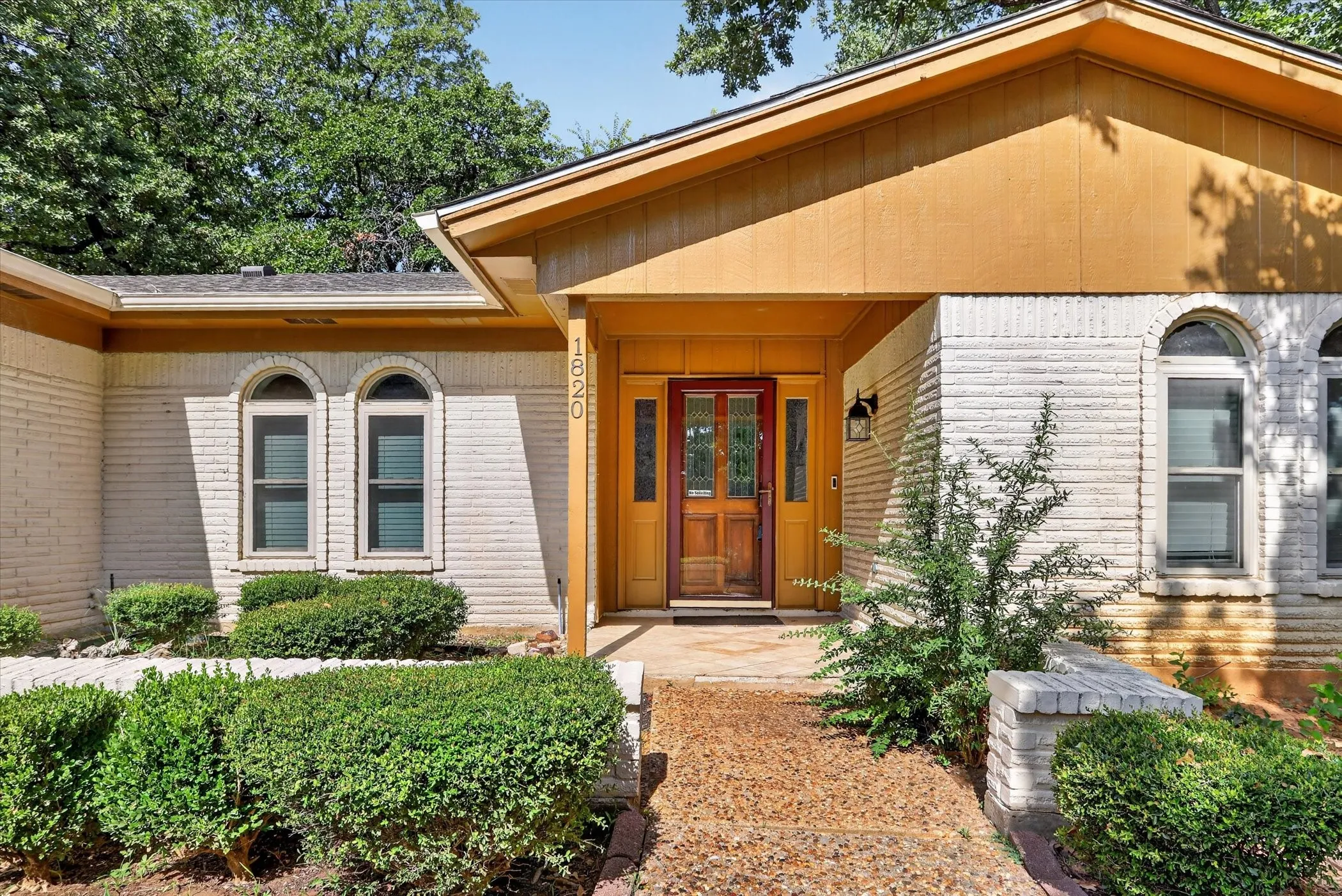 White brick exterior with a warm wood-tone front door