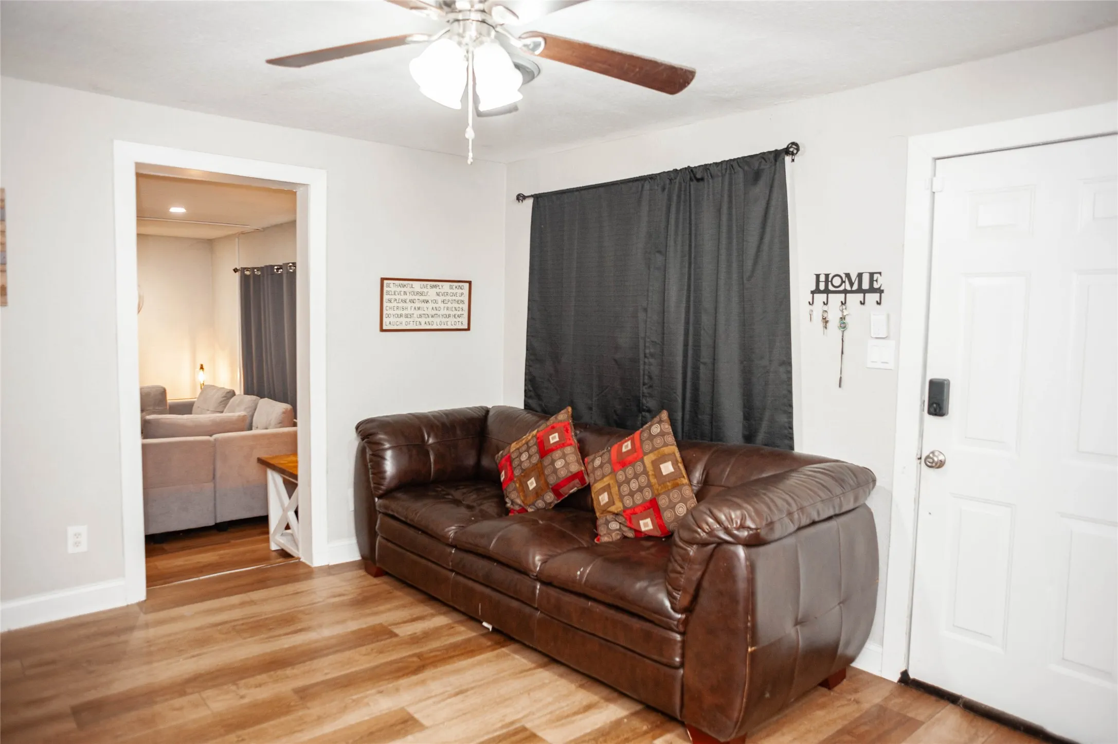 Wood-finish flooring throughout, ceiling fan with light fixture, and light gray wall paint