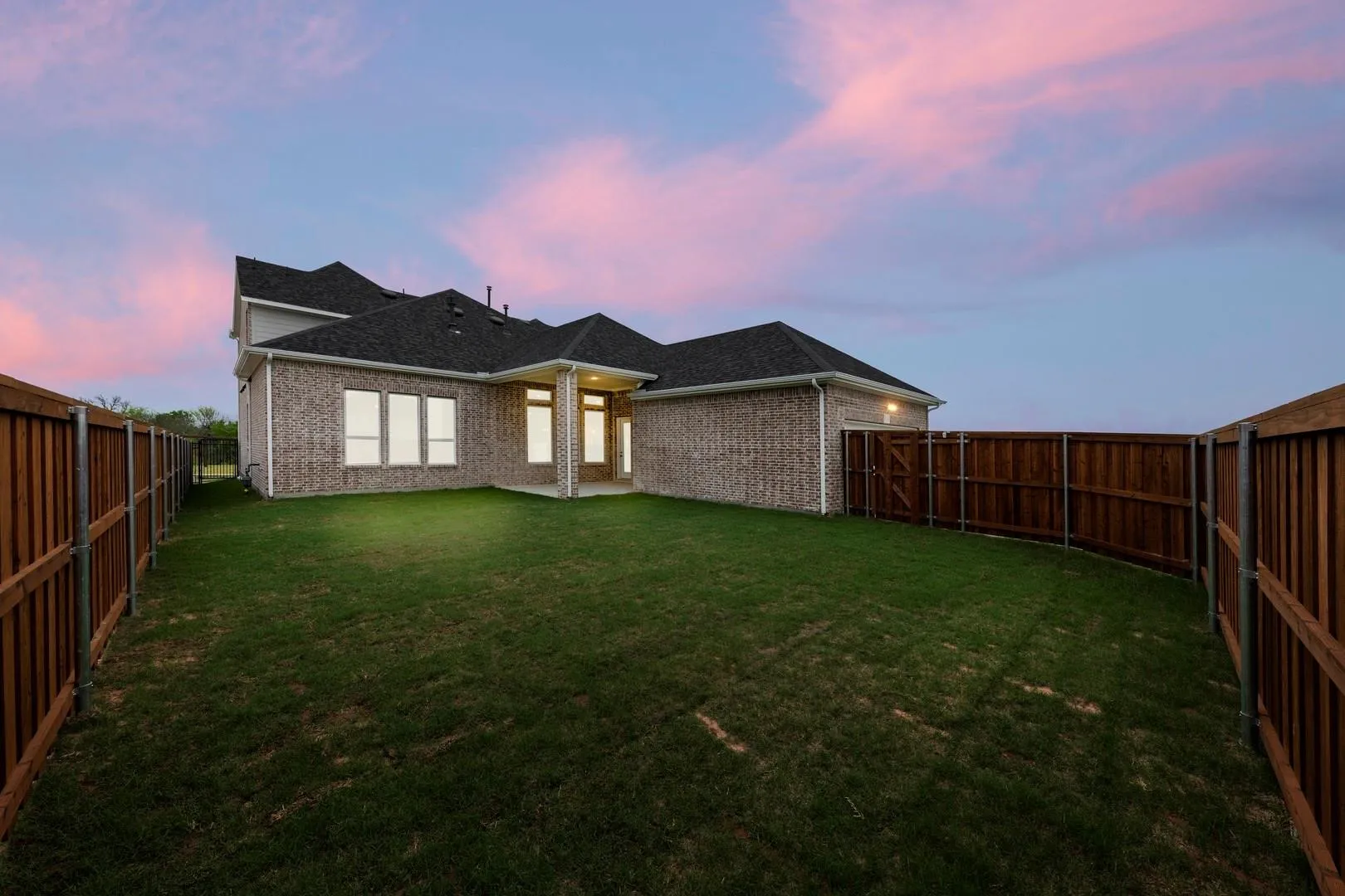 Expansive backyard featuring a manicured lawn bordered by privacy fencing on both sides