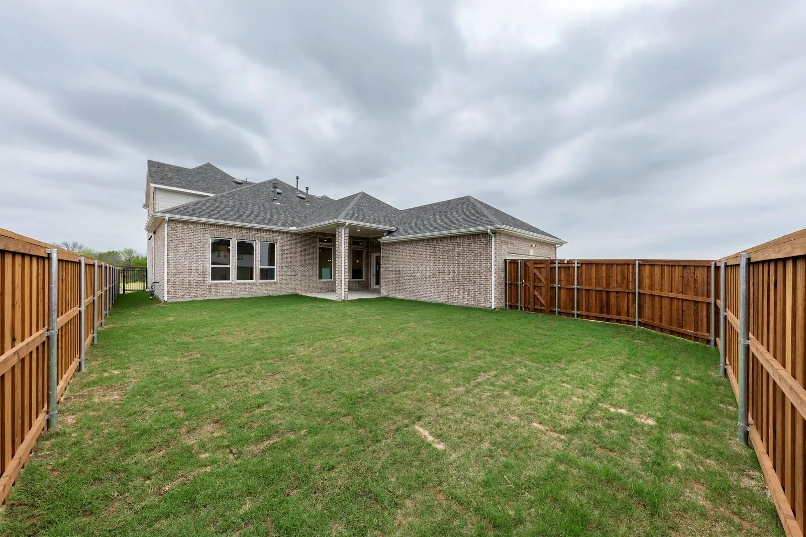 Expansive backyard featuring a generously sized manicured lawn bordered by wood-finish privacy fencing