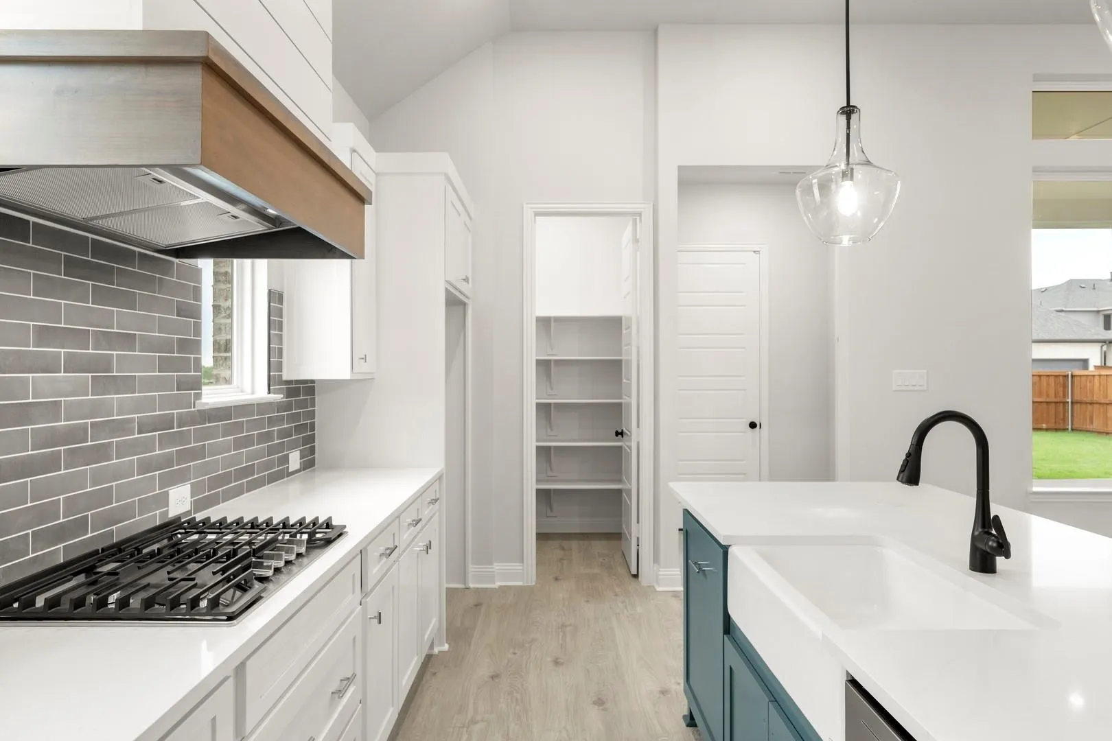 Modern kitchen featuring white cabinetry, a gas cooktop with stainless steel hood, subway tile backsplash, and quartz countertops