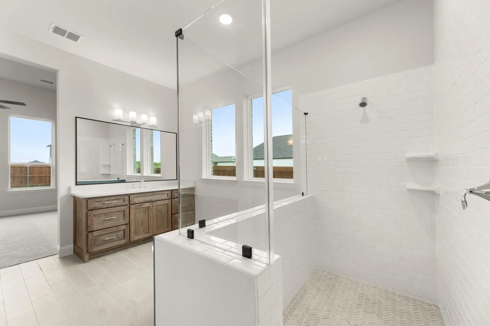 Walk-in shower with clear glass enclosure and white subway tile walls