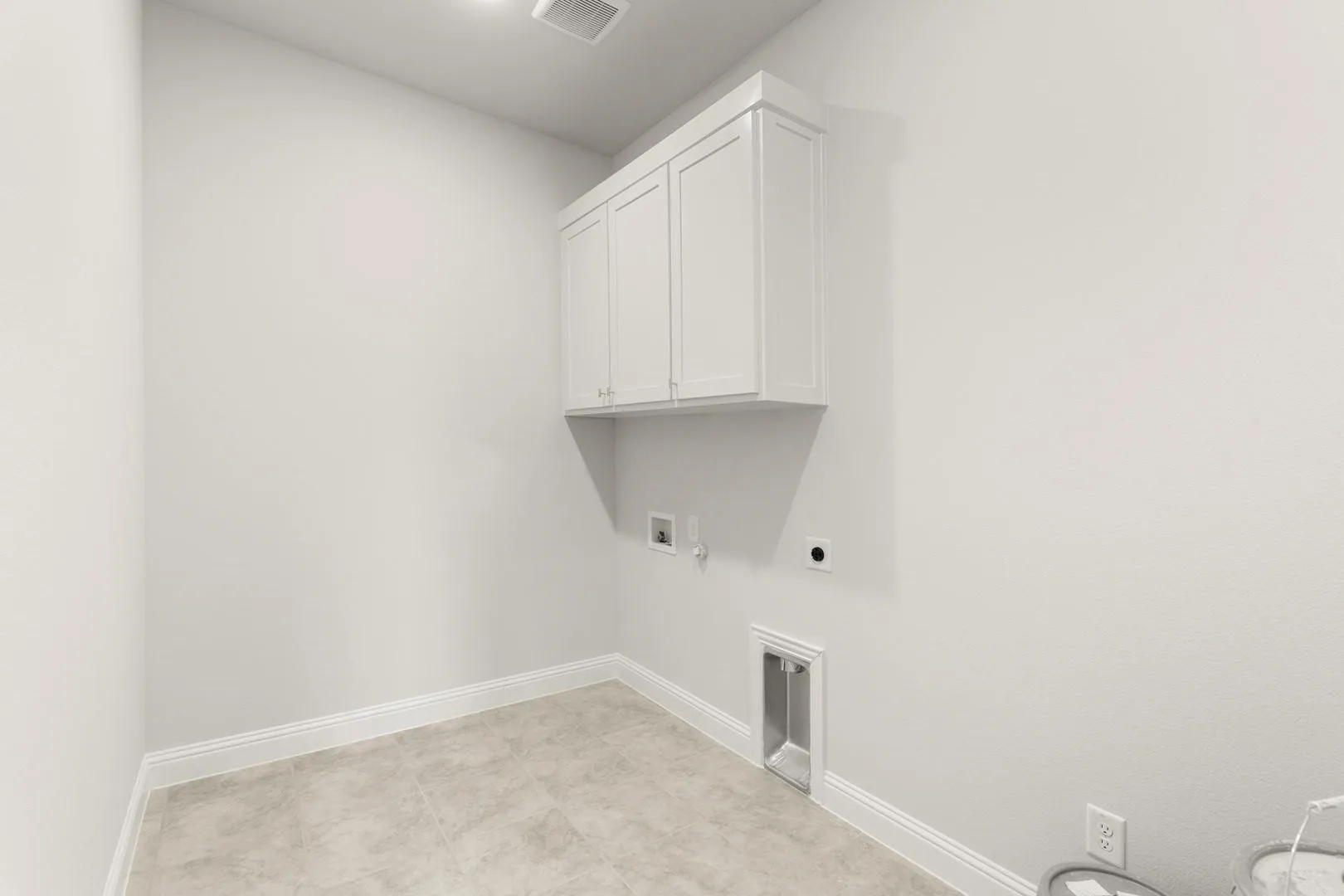 Utility space featuring neutral wall paint, tiled flooring, white shaker-style cabinetry, and baseboard molding