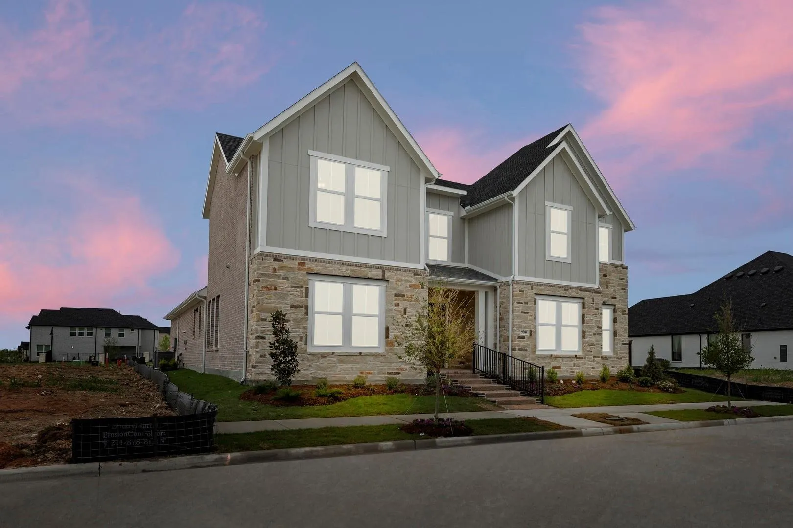 Contemporary residence featuring a stone and board-and-batten facade, multiple gables, and dark shingle roofing