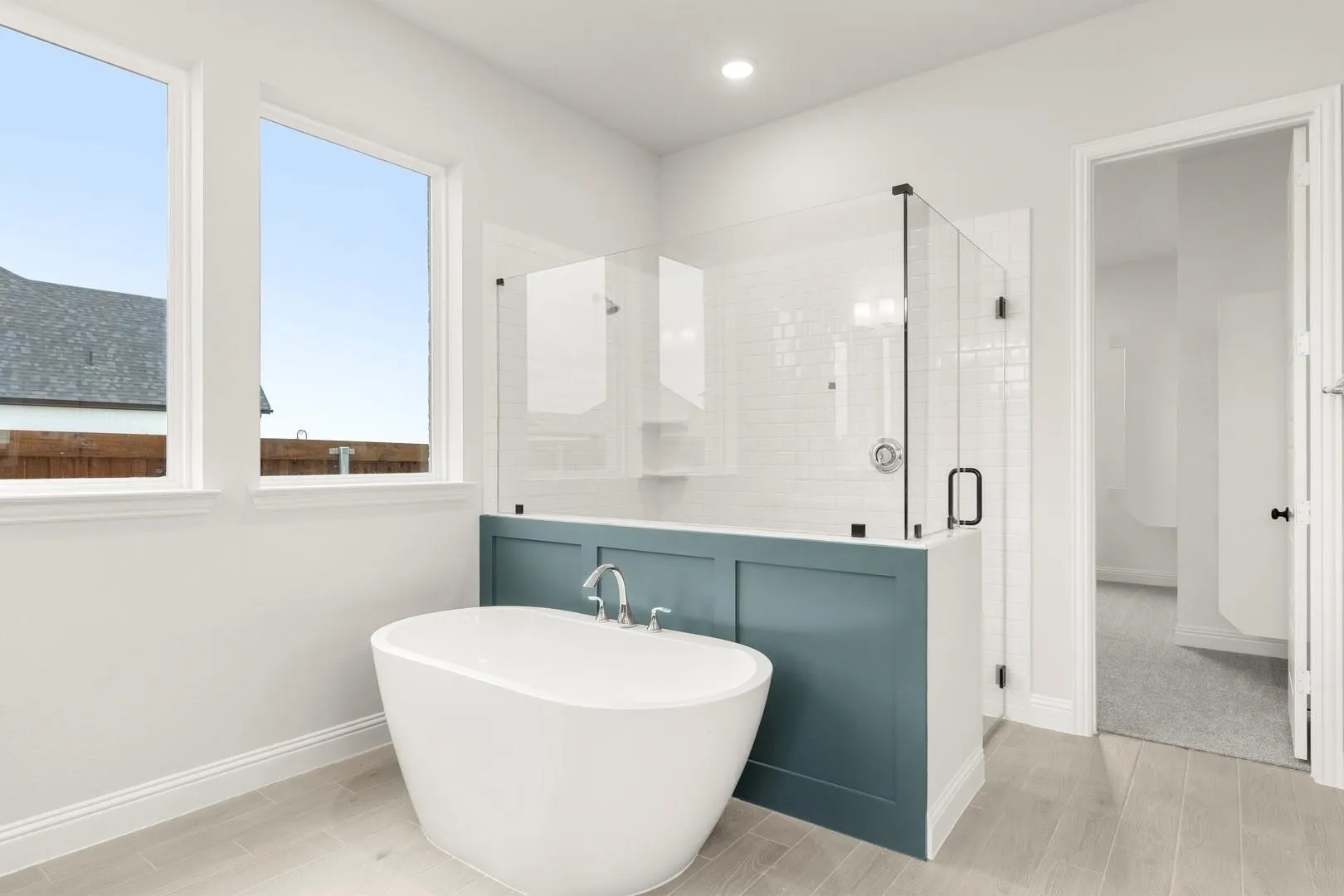 Soaking tub with chrome fixtures, glass-enclosed shower featuring subway tile, recessed lighting, and light-toned wood-finish flooring