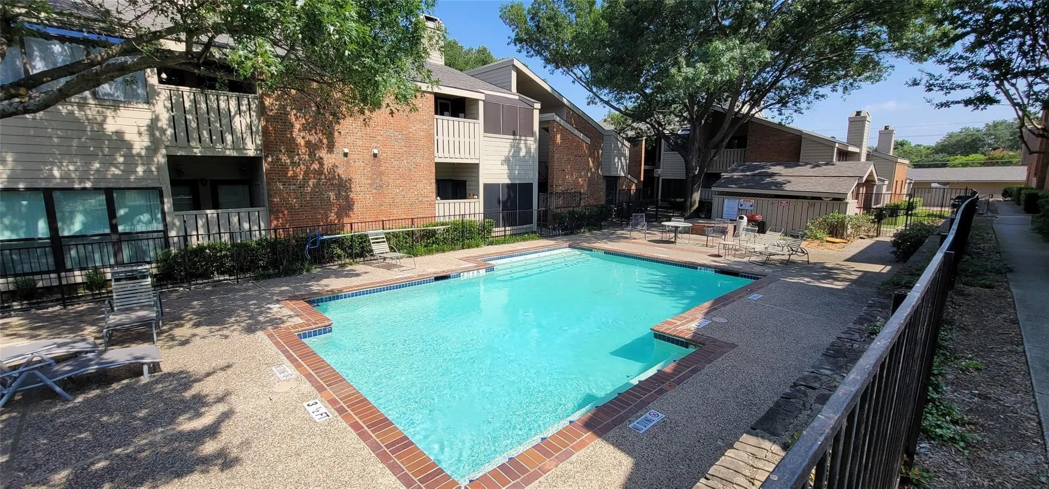 Sparkling swimming pool with brick coping, surrounded by a textured concrete deck