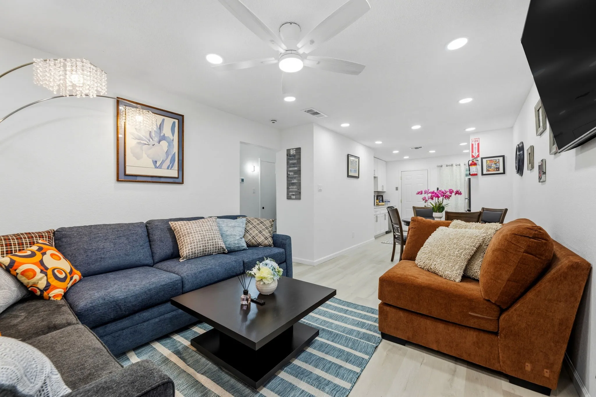 Open-concept living area with light wood-finish flooring, recessed lighting, and a ceiling fan