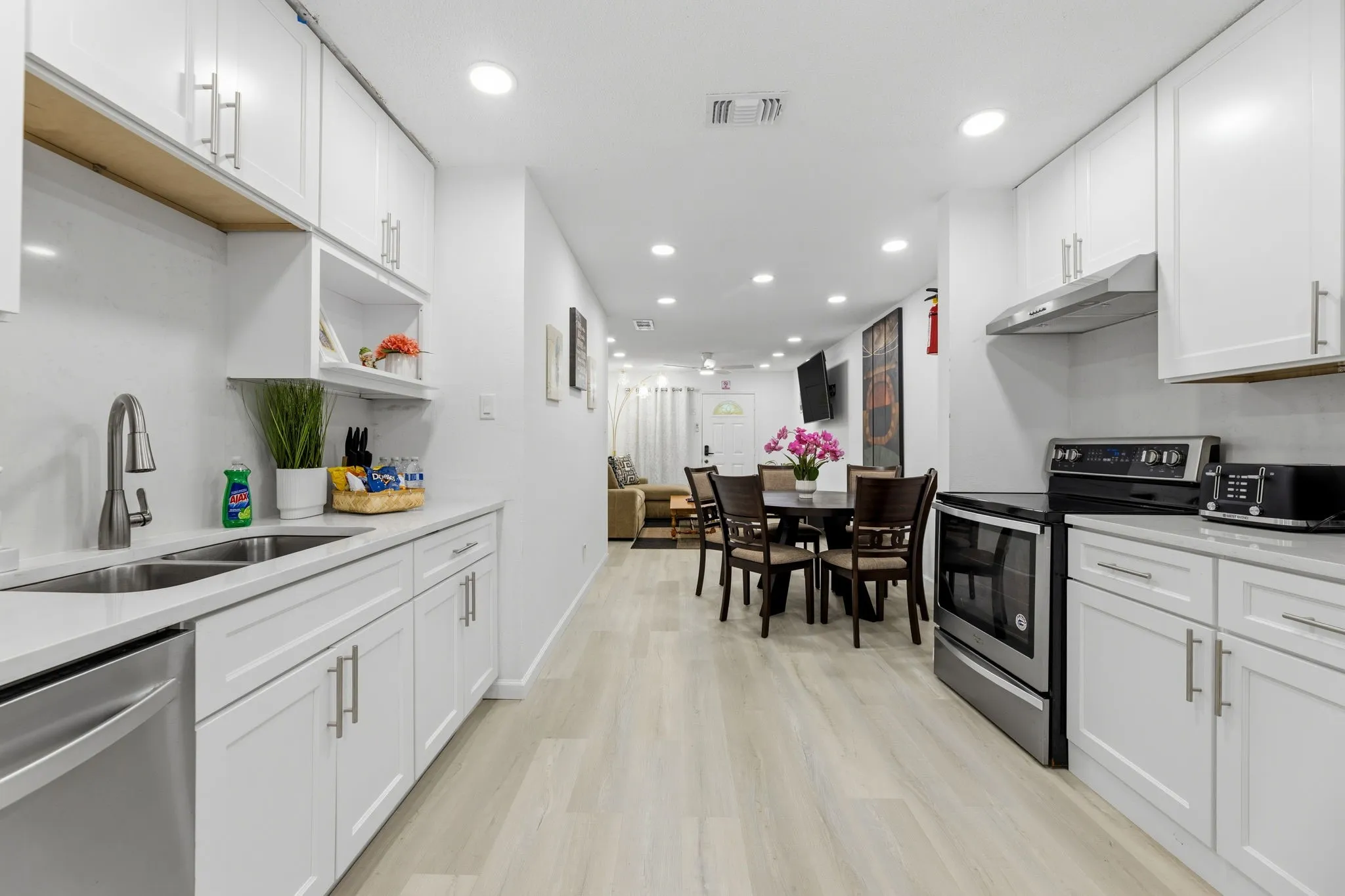 Modern kitchen featuring white cabinetry, light-toned wood-finish flooring, recessed lighting, stainless steel appliances, and sleek countertops