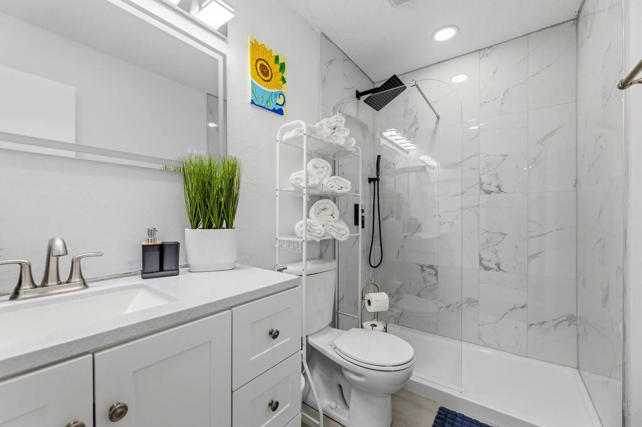 Contemporary bathroom featuring a white vanity with integrated sink, brushed nickel faucet, and a large mirror