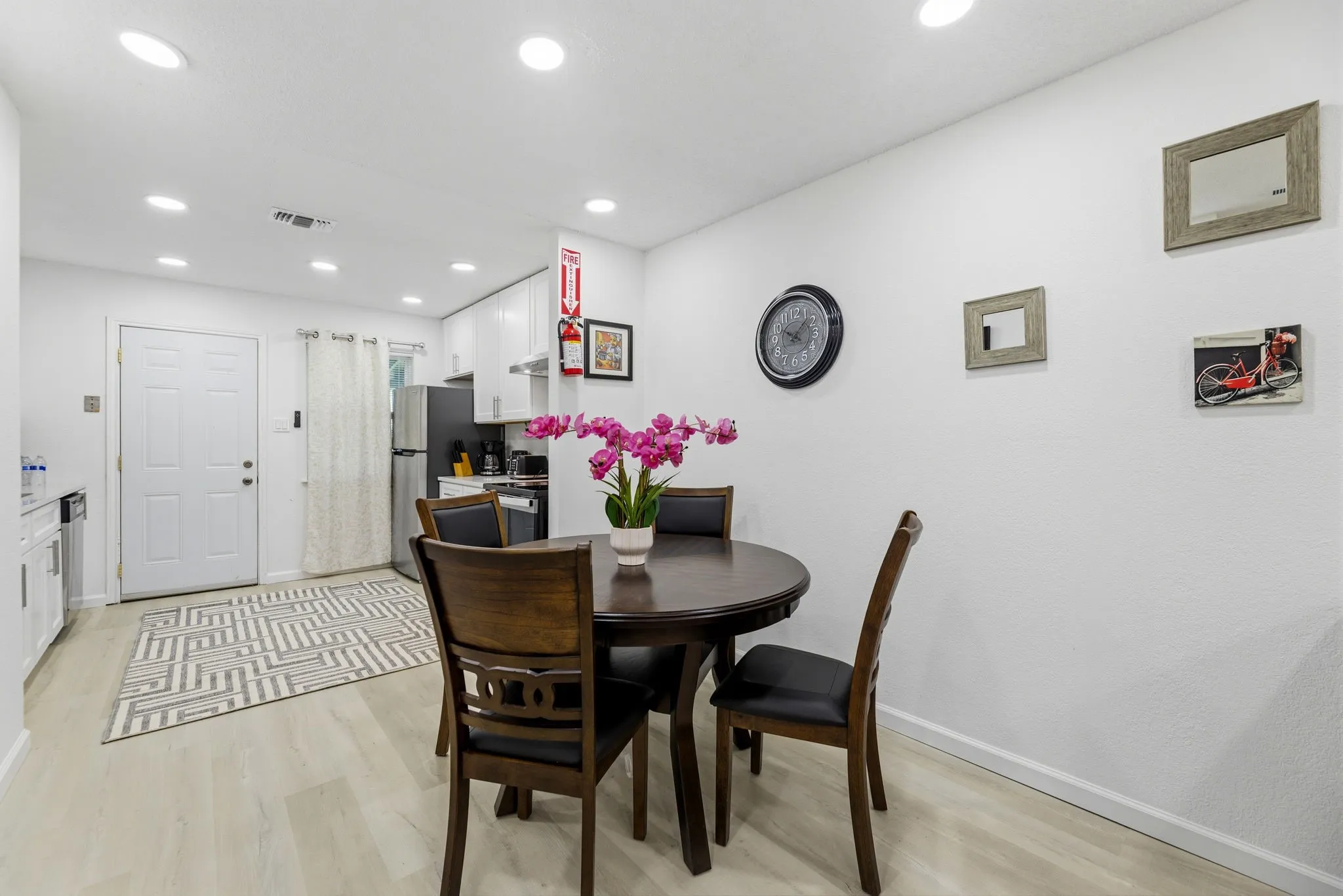 White kitchen cabinetry with stainless steel appliances, recessed ceiling lighting, and light wood-finish flooring