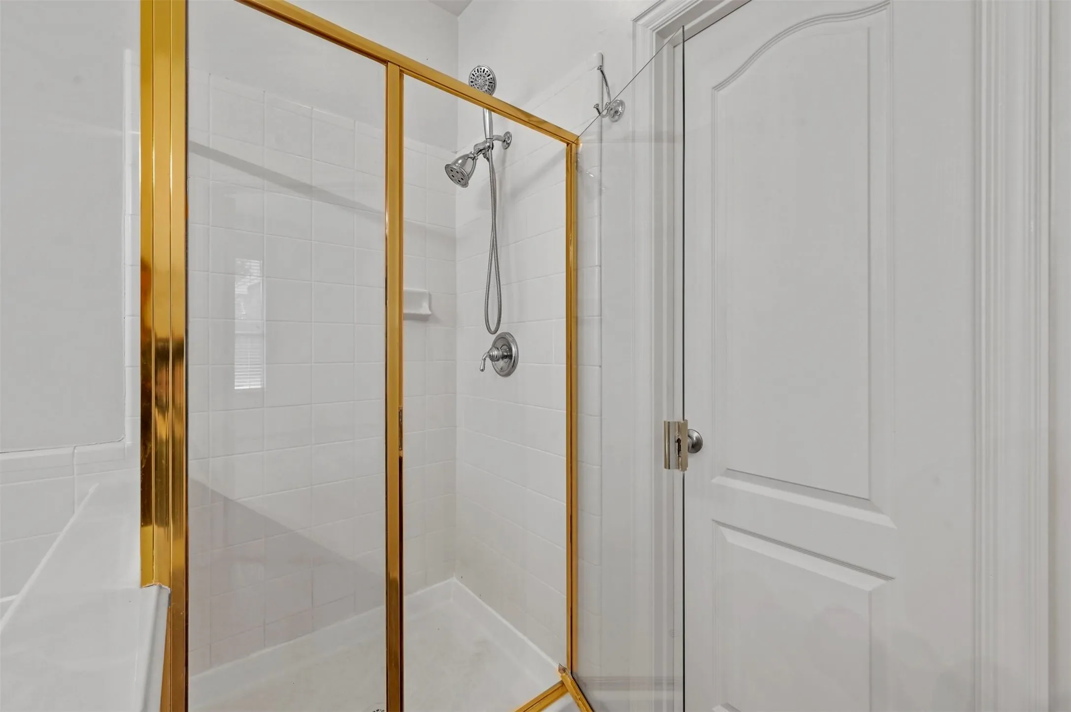 Shower enclosure featuring a gold-finish frame and clear glass panels